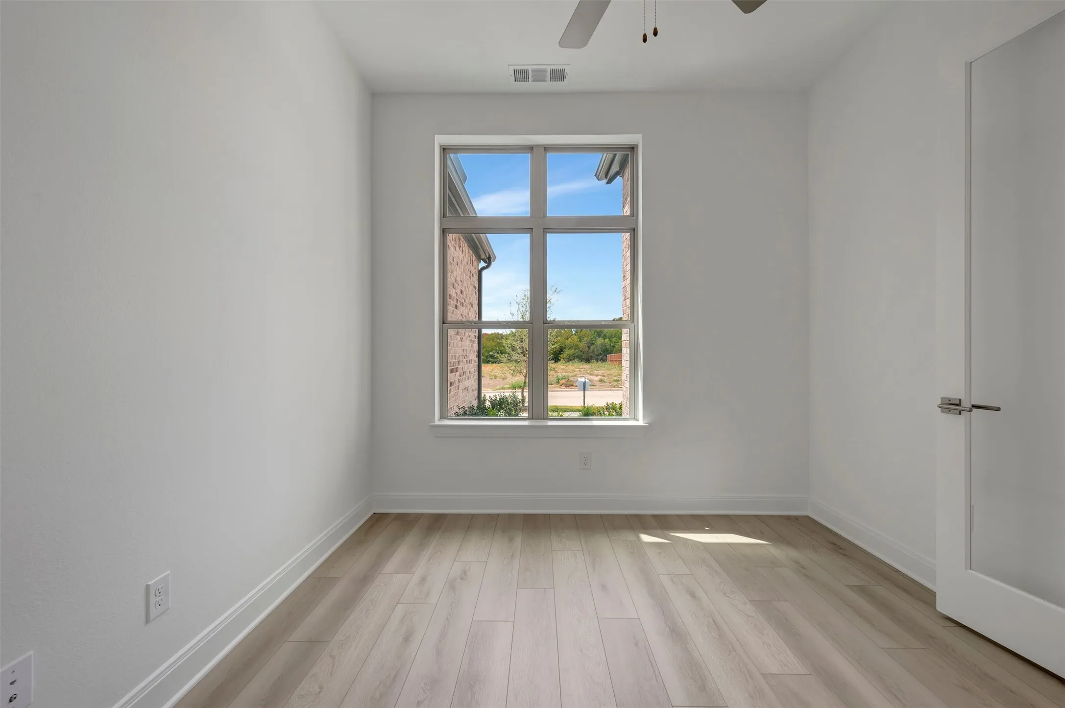 Wood-finish flooring, white painted walls, and a multi-pane window
