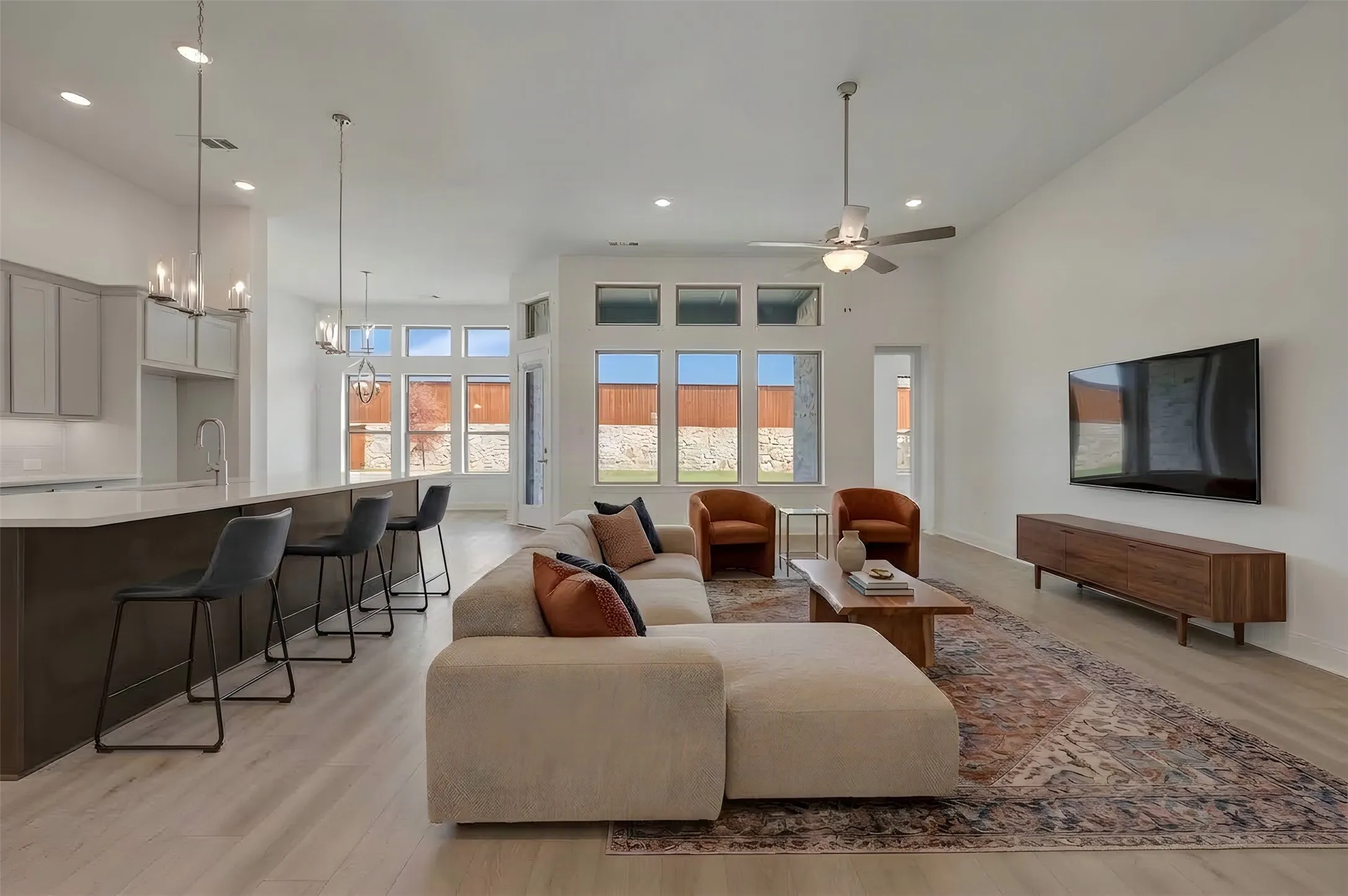 Open-concept living area with vaulted ceilings, wood-finish flooring, and ample natural light from multiple windows