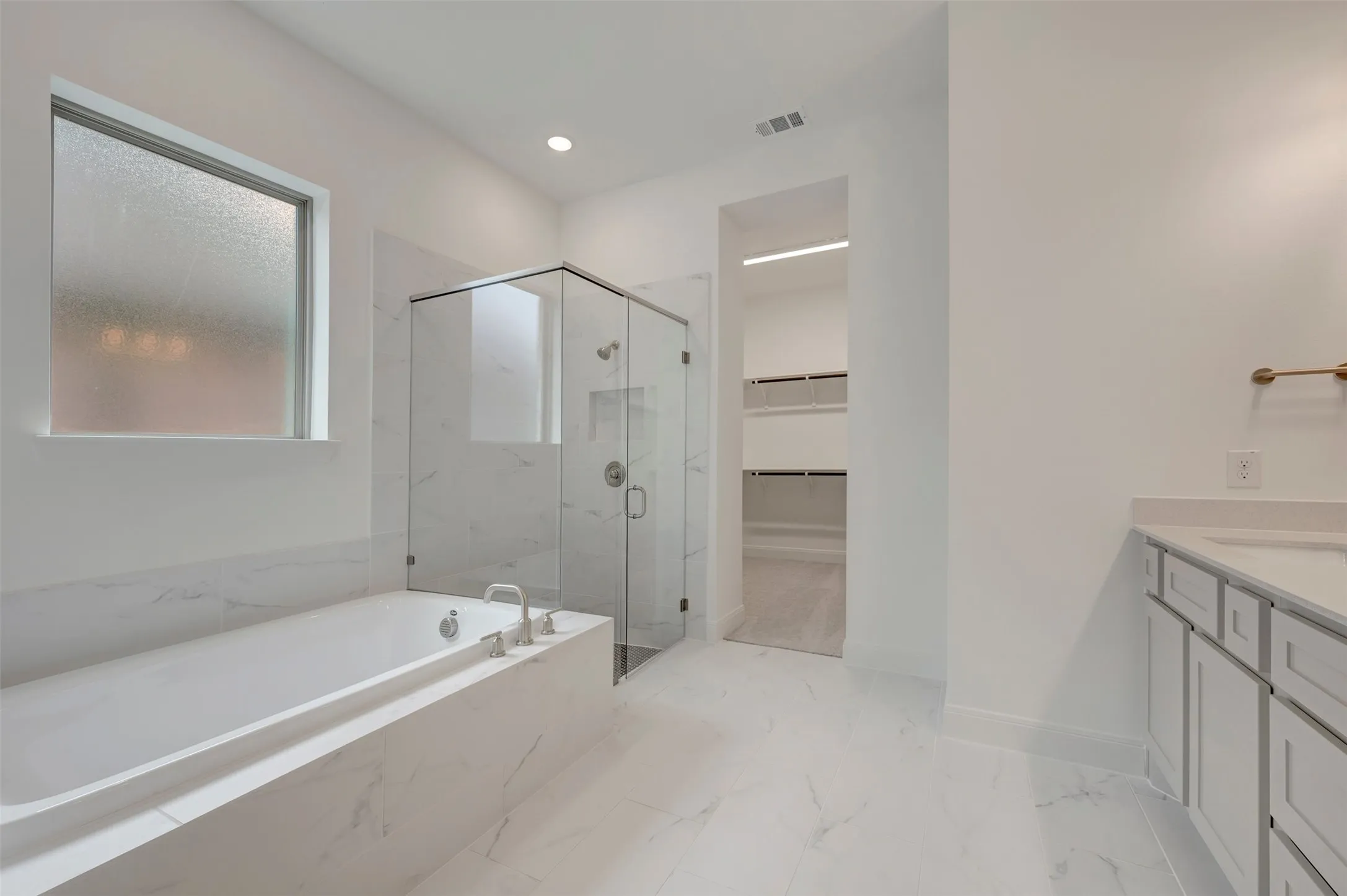 Sleek bathroom featuring a built-in soaking tub, walk-in shower with glass enclosure, single vanity with undermount sink, and recessed lighting