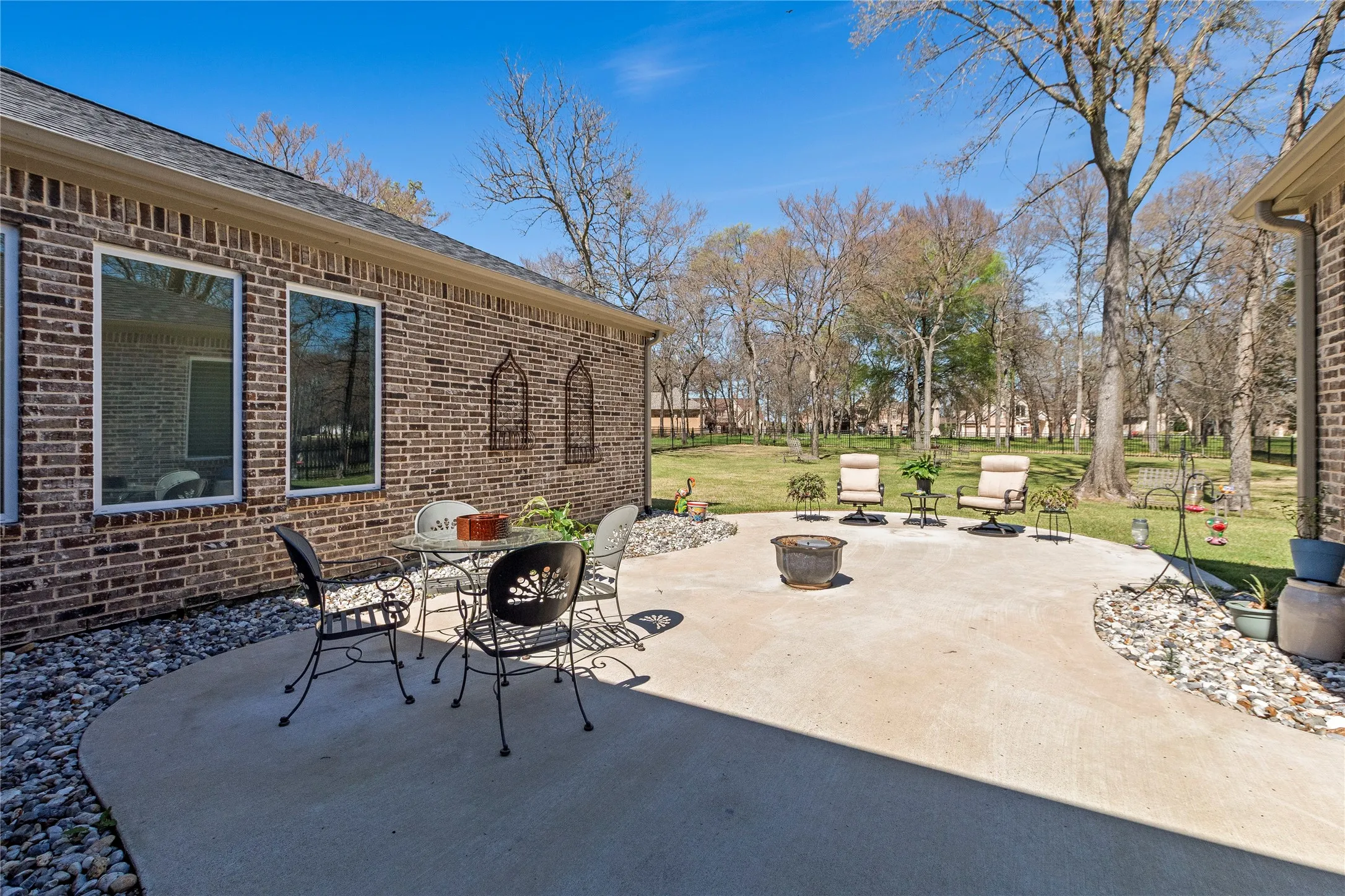 Spacious concrete patio overlooking large fenced in yard.