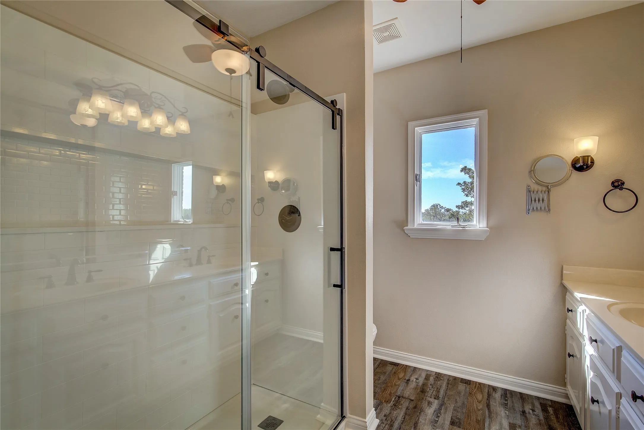 upstairs primary bath has oversized walk in shower with glass doors, double vanity
