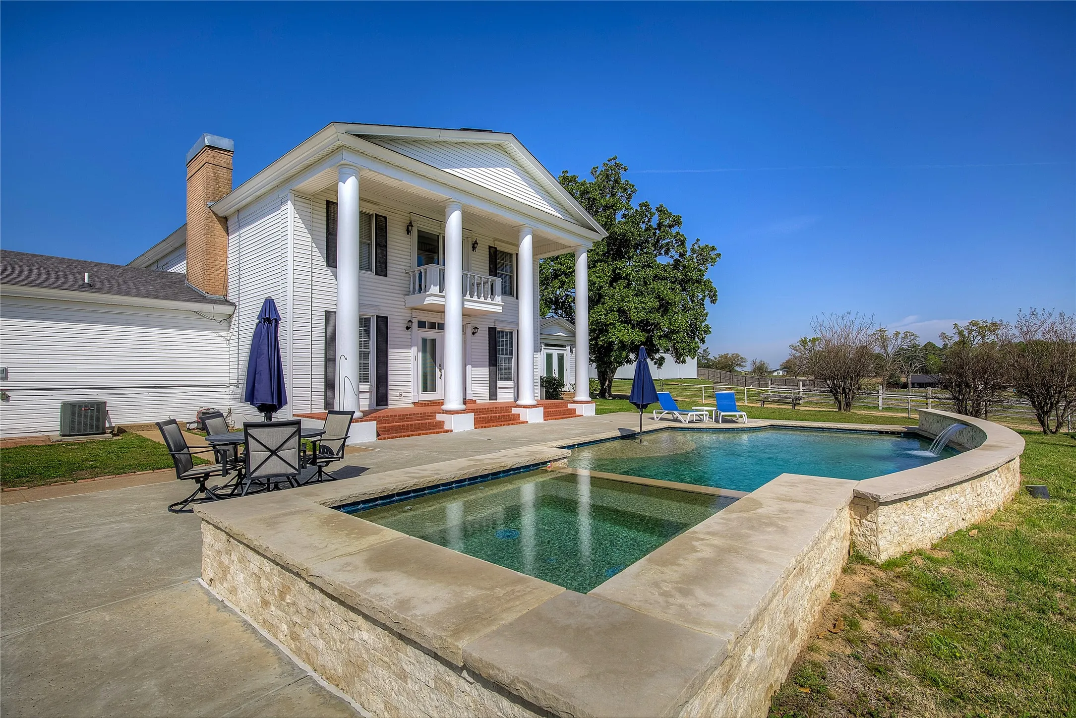 Swimming pool with two waterfalls, hot tub, concrete decking