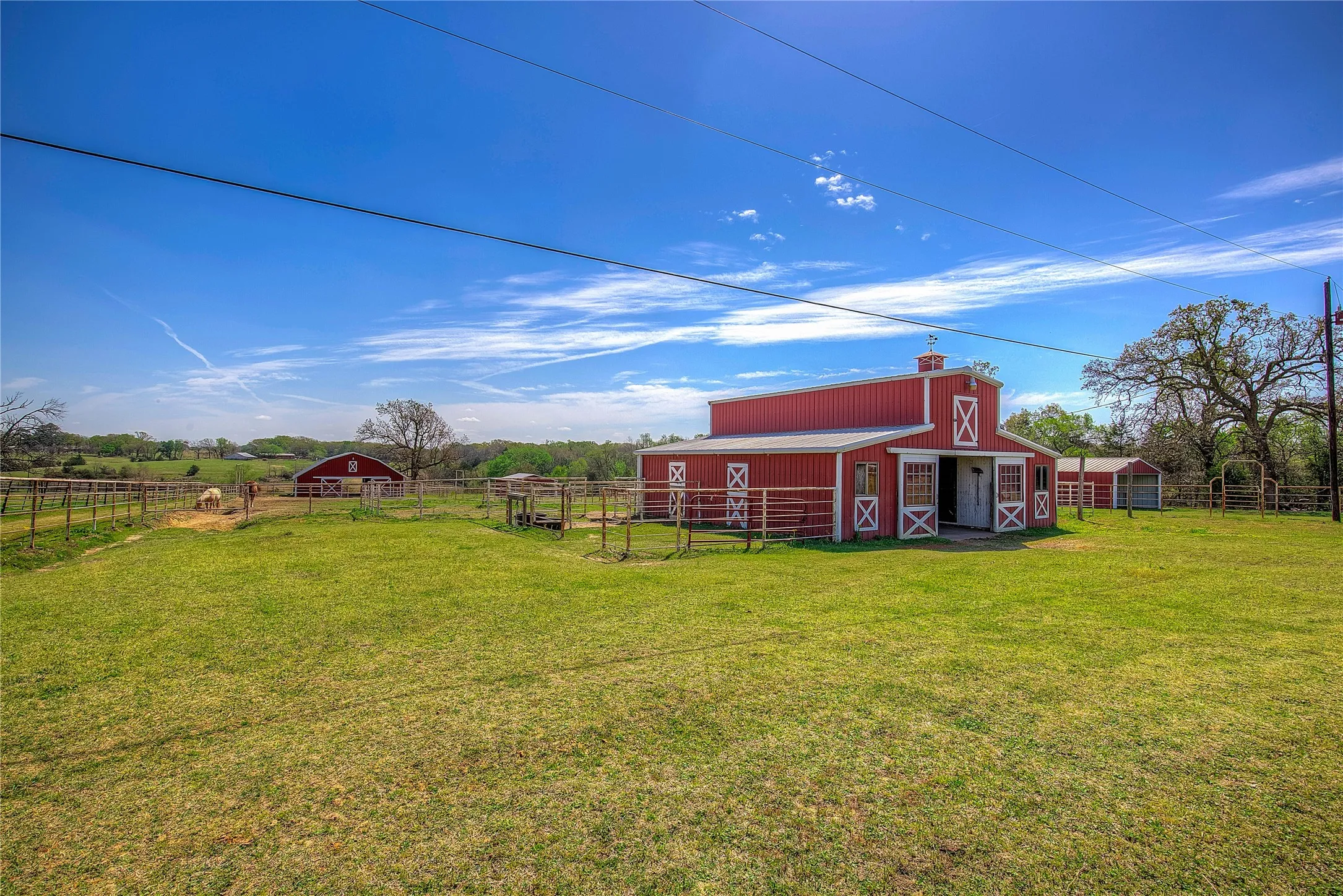 One of THREE stables on property; this one has four stalls, tack room, hay storage. Another stable is visible in background
