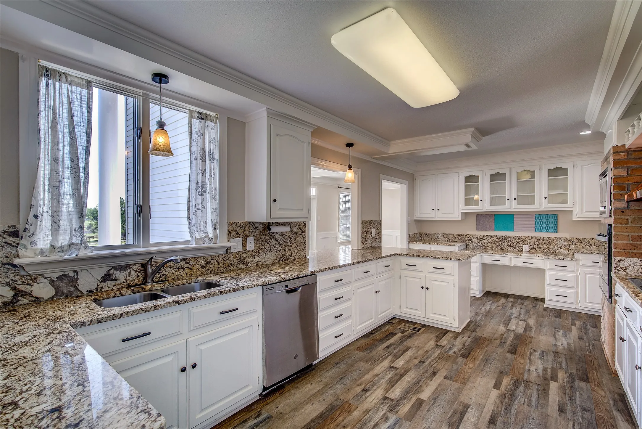 Kitchen has custom walnut cabinets, granite counters/backsplash, double window over sink, desk area, breakfast bar.