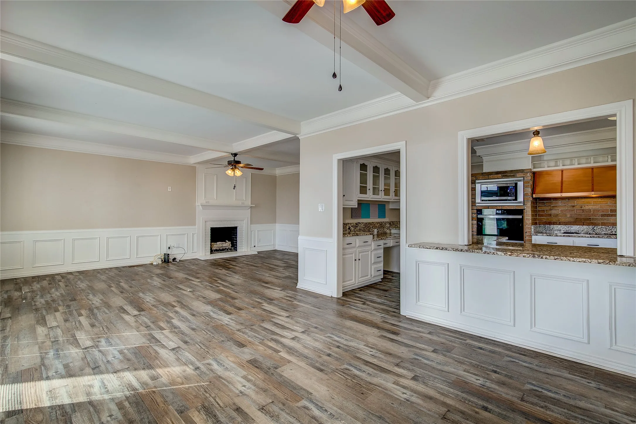 breakfast area with great room beyond; pass through to kitchen; note the ceiling beams, wainscoting, crown molding, and fireplace with hearth
