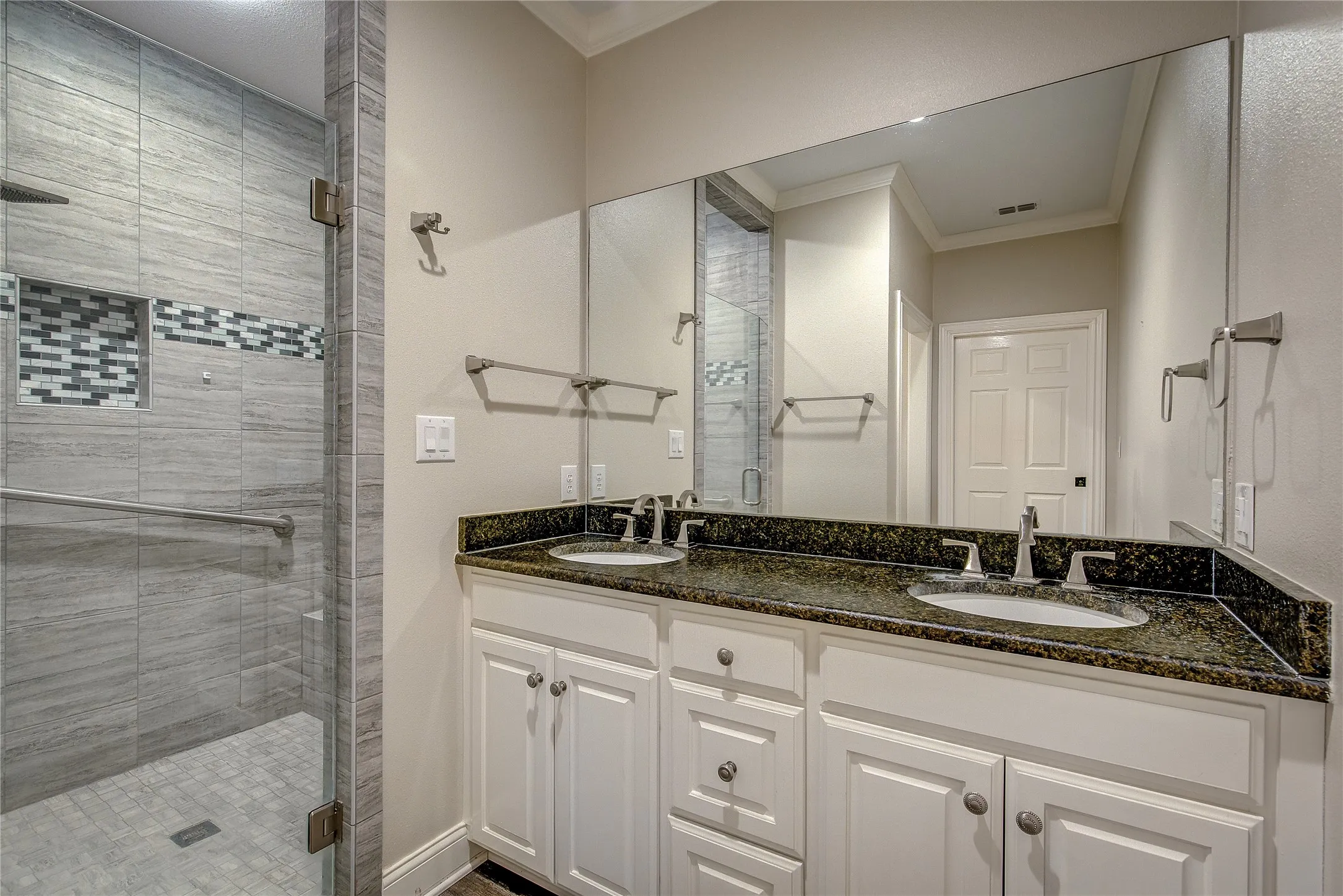 downstairs primary bath has fully-tiled oversized shower with glass door, double vanity with granite, separate potty.