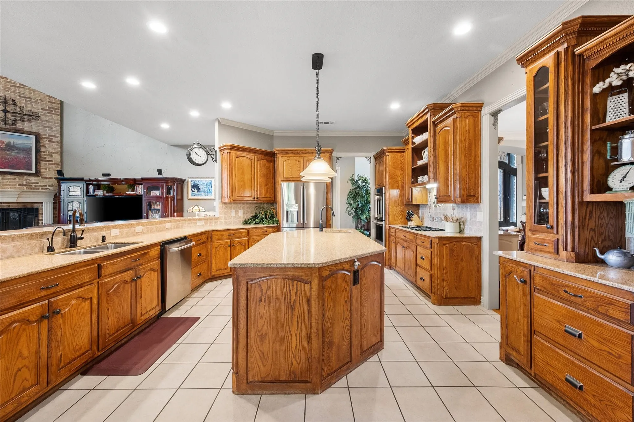 Kitchen featuring an island with sink, wood finish cabinetry, stainless steel appliances and hanging light fixtures!