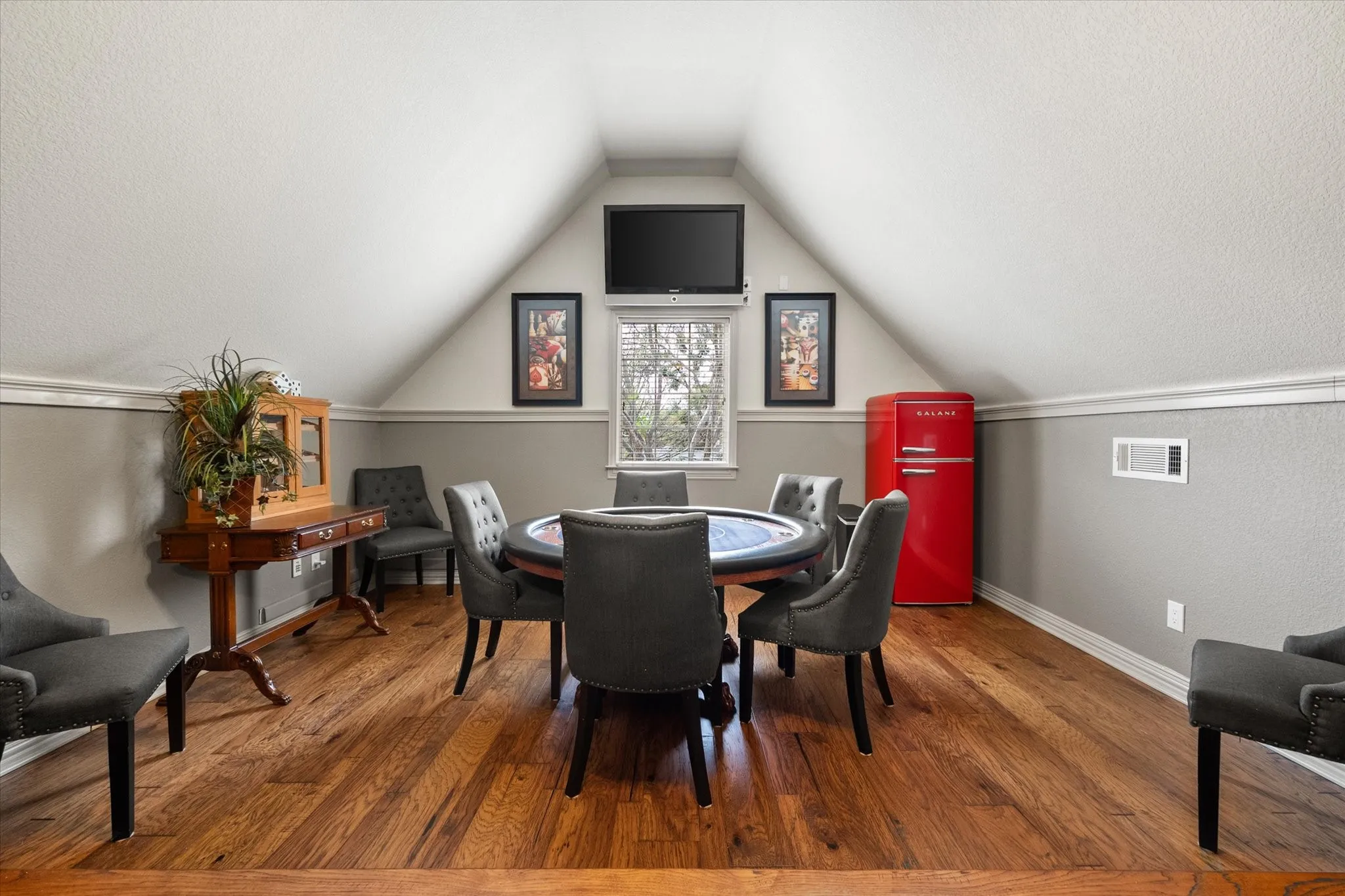 Game room with pool table, poker table and TV.  With wood finished floors and a textured ceiling