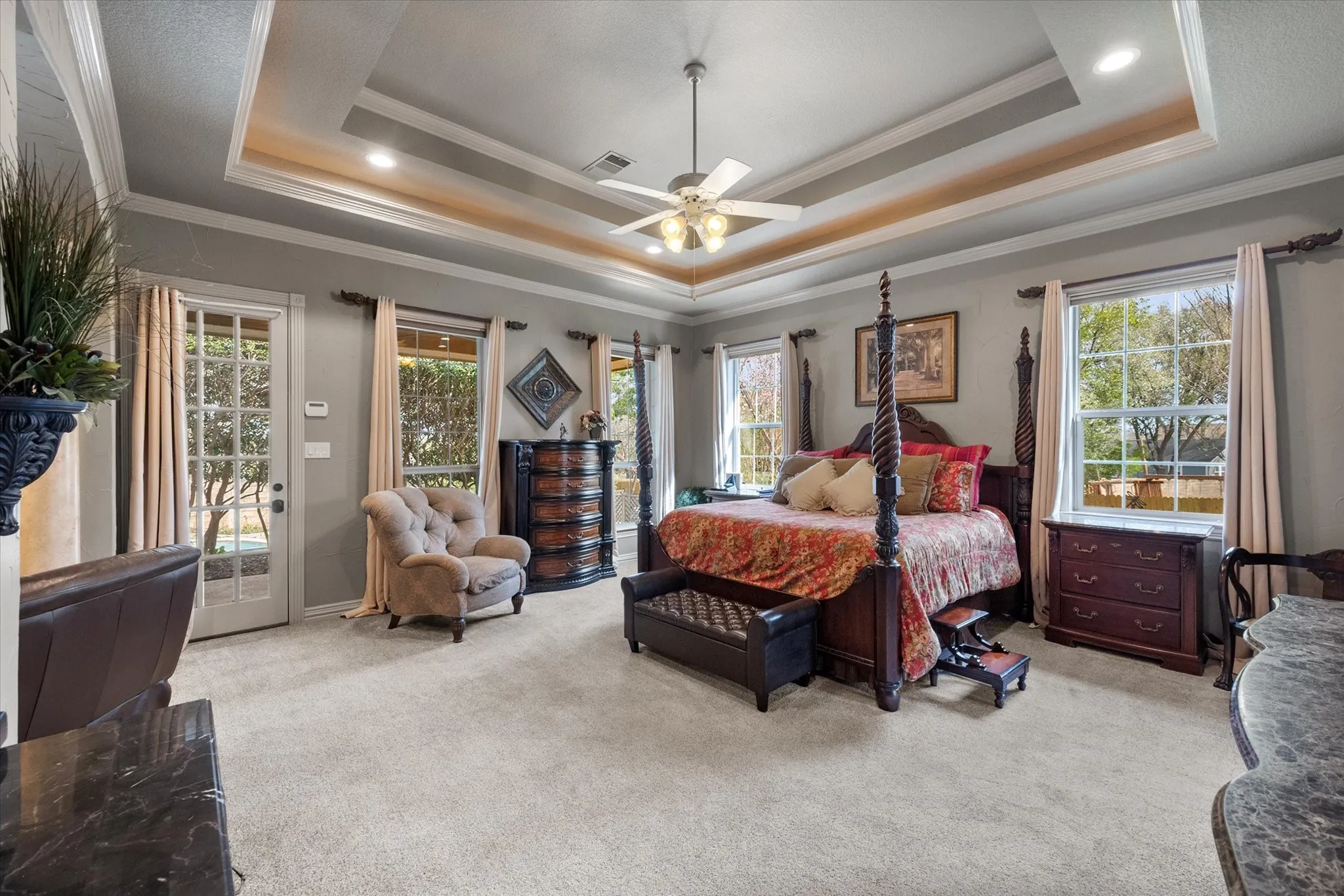 Master suite featuring light carpet, ornamental molding, a ceiling fan, multiple windows, and access to outside
