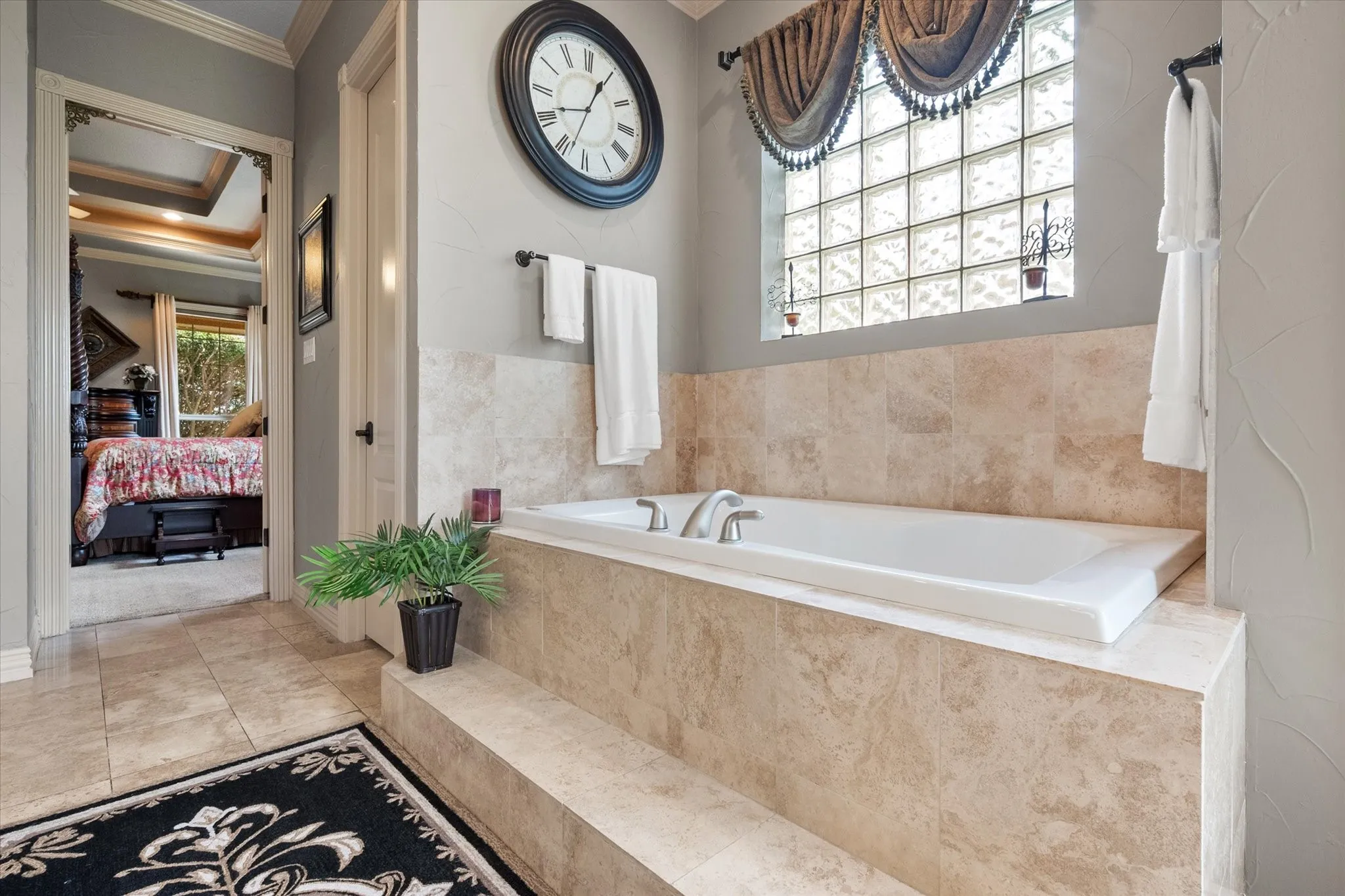 Full ensuite bathroom with ensuite bath, crown molding, a garden tub, and light tile patterned floors