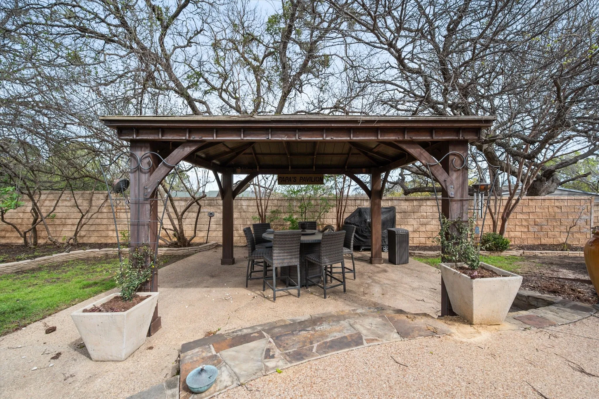 Outdoor gazebo with a gravel base, flagstone pathway, and perimeter landscaping