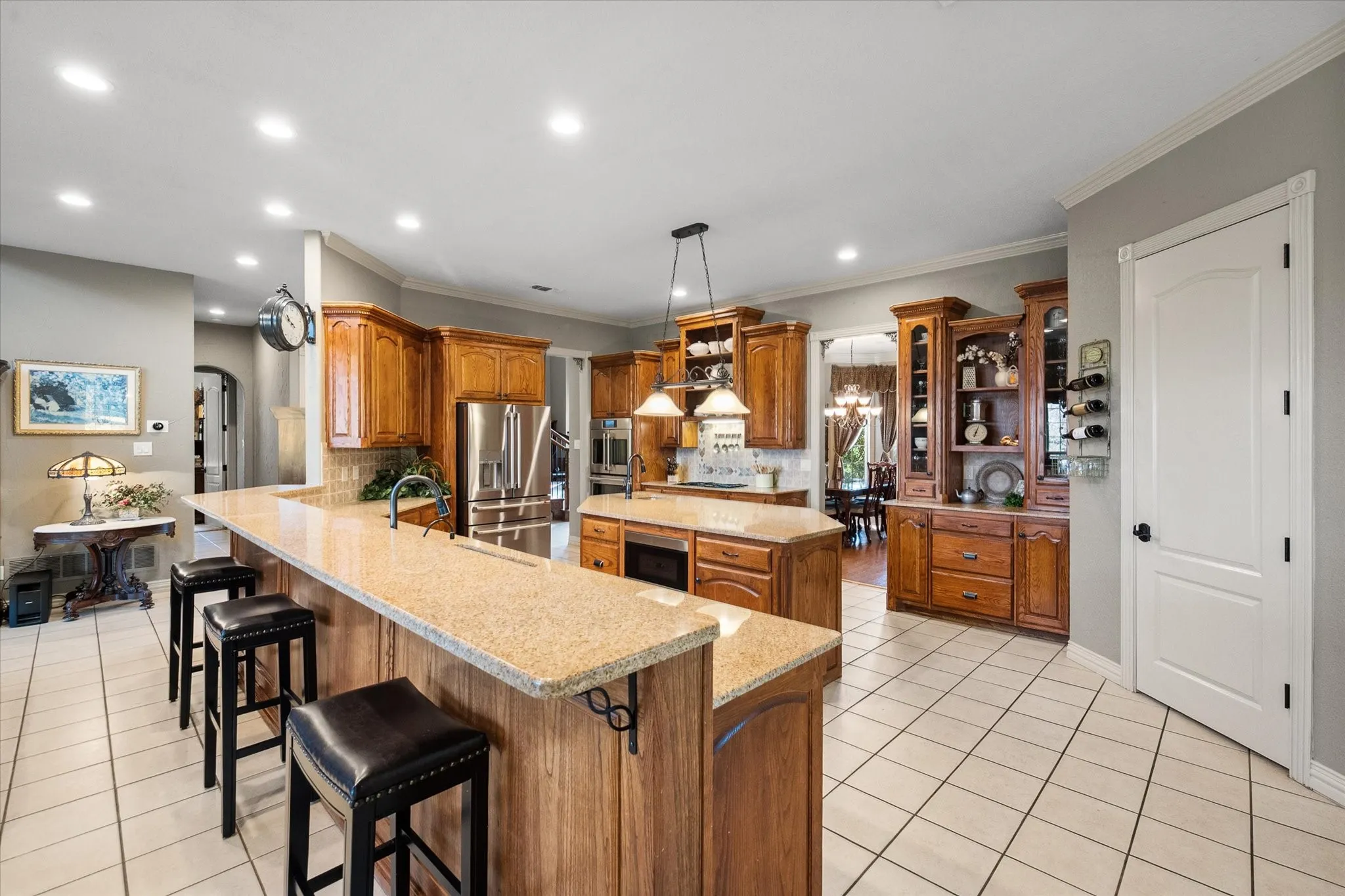 Kitchen featuring wood finish cabinetry, arched walkways, light tile patterned floors, crown molding, and stainless steel appliances