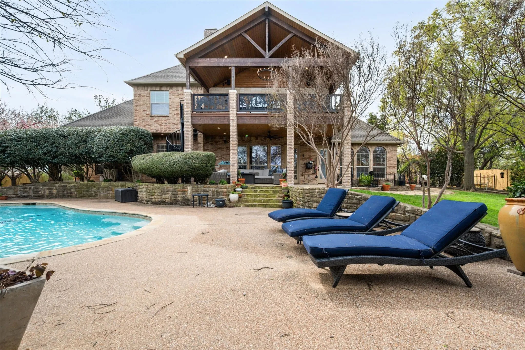 Rear view of property with a patio area, a balcony, brick siding, and an outdoor pool