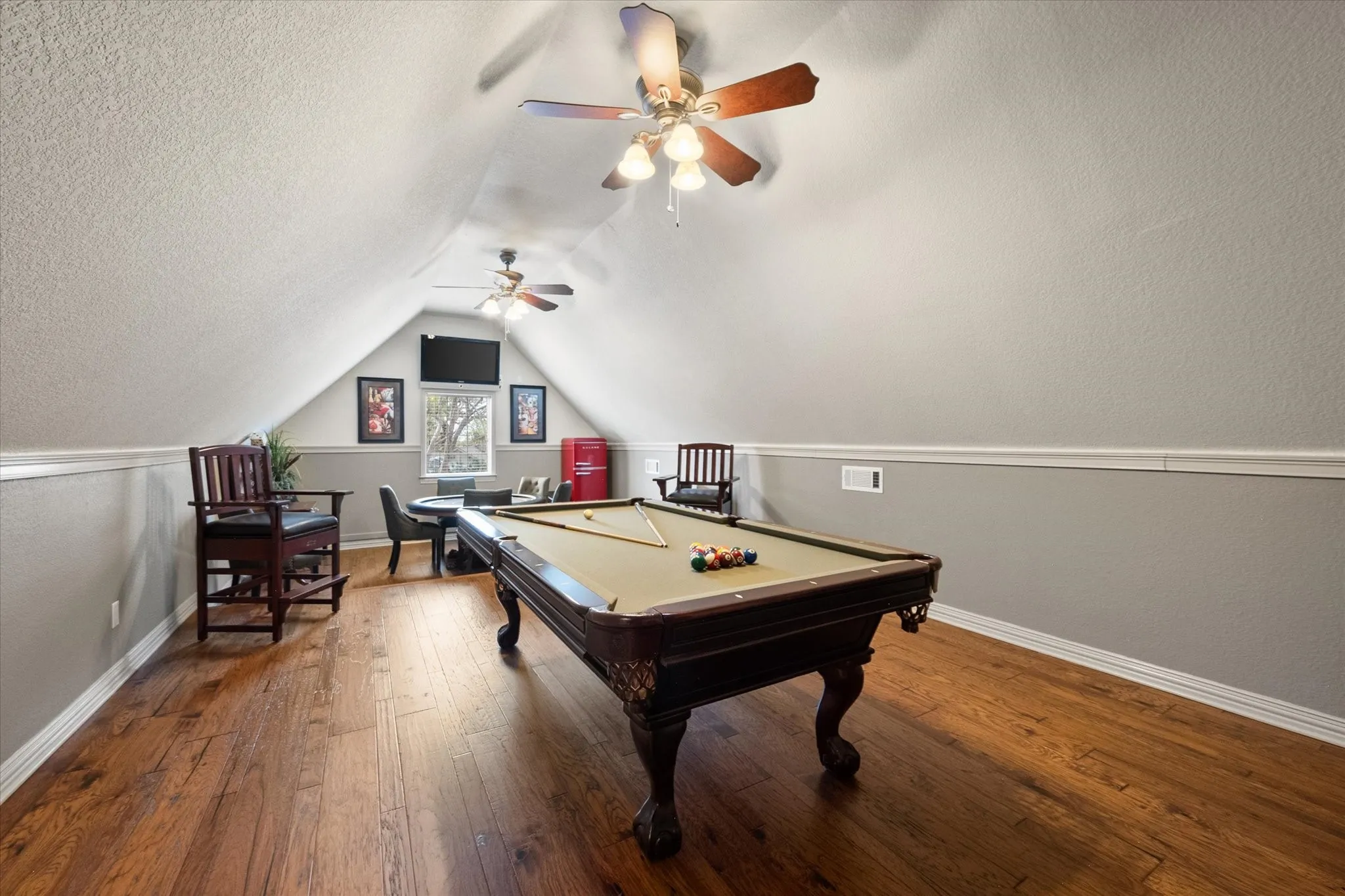 Gameroom featuring wood-finish flooring, an angled ceiling, two ceiling fans, and a window!