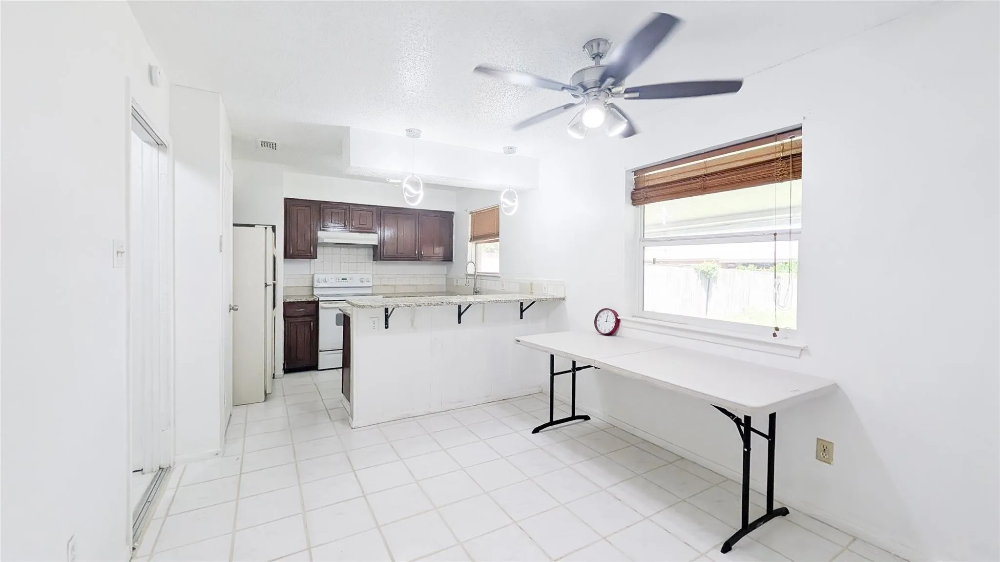 Kitchen with a kitchen bar, light countertops, a peninsula, decorative backsplash, and white electric range oven