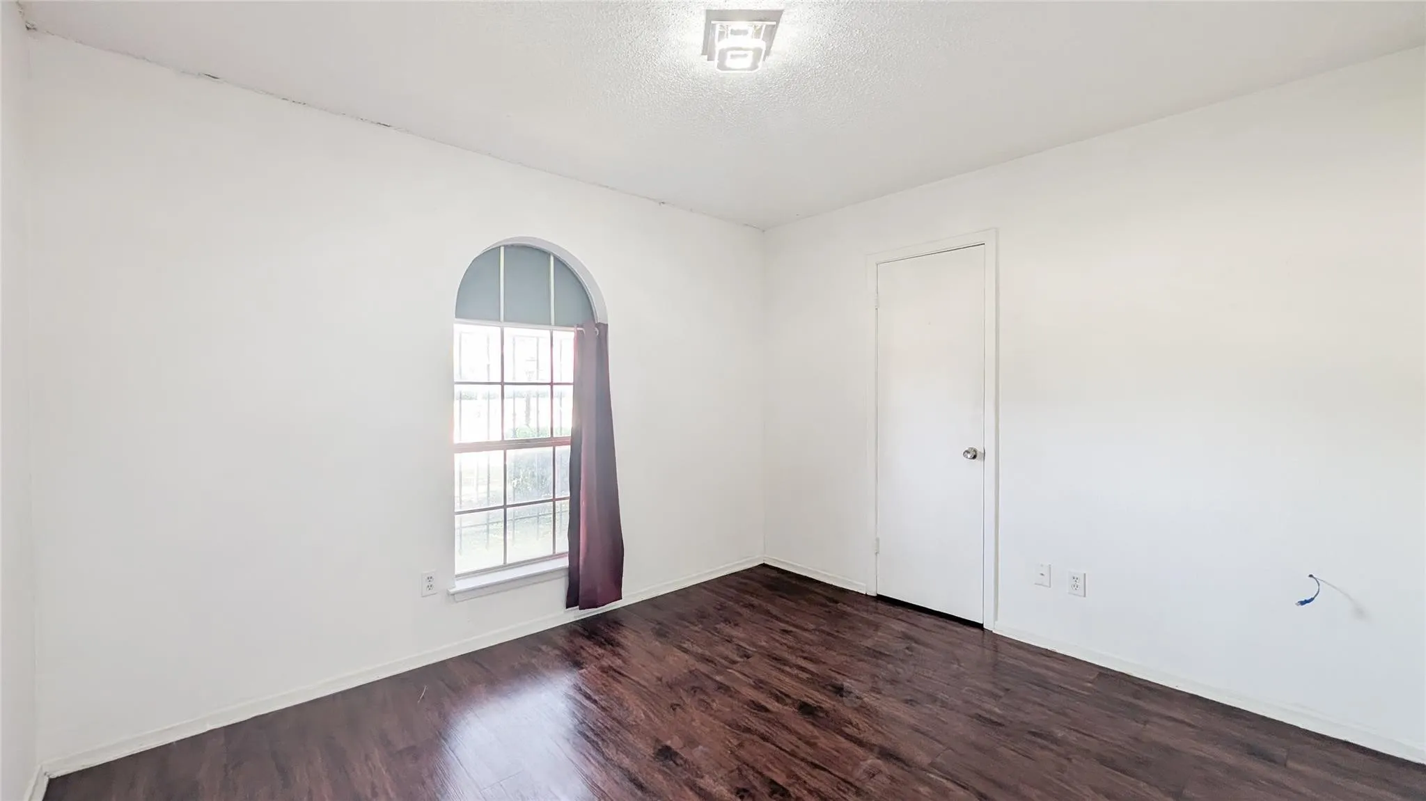 Empty room with dark wood-type flooring and a textured ceiling