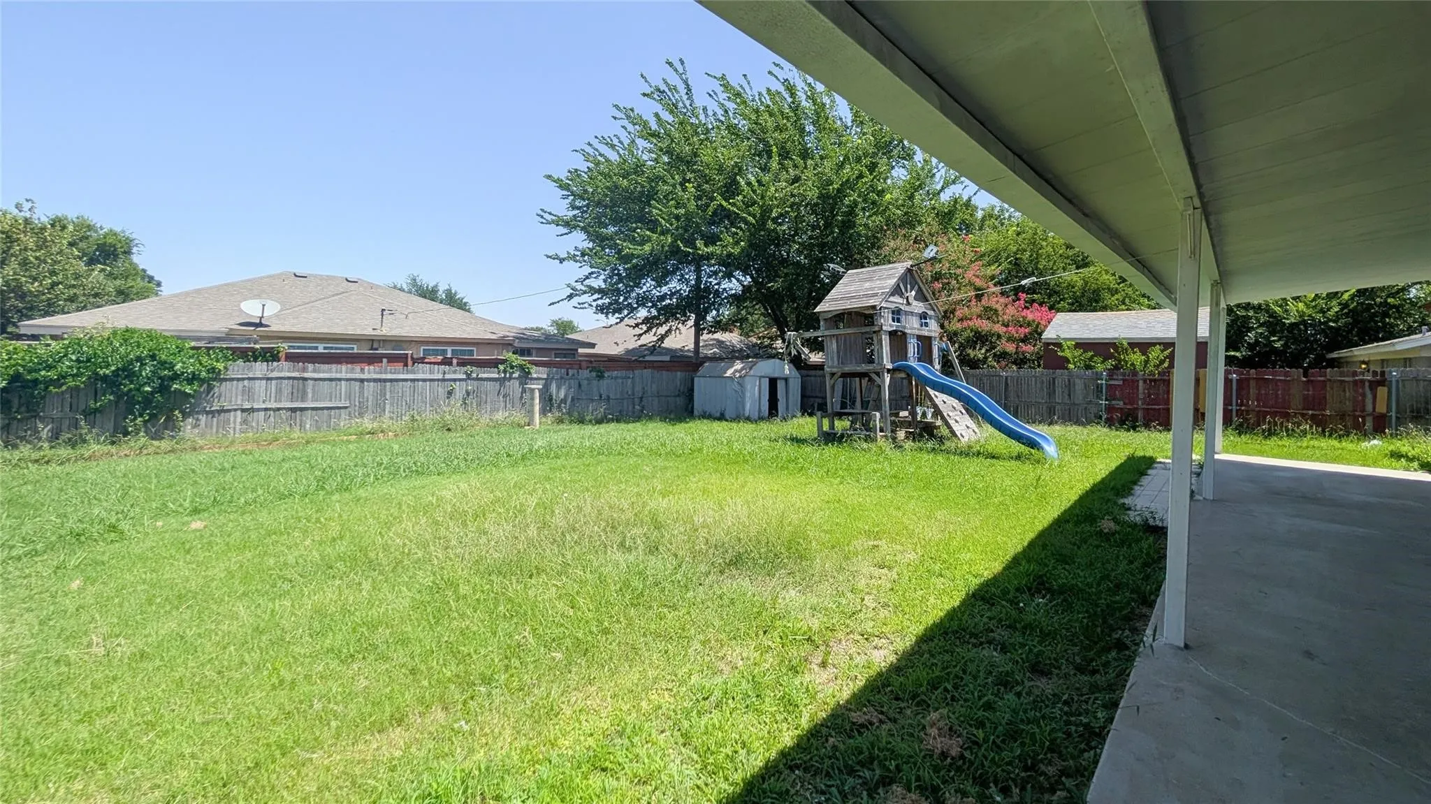 Fenced backyard featuring a playground