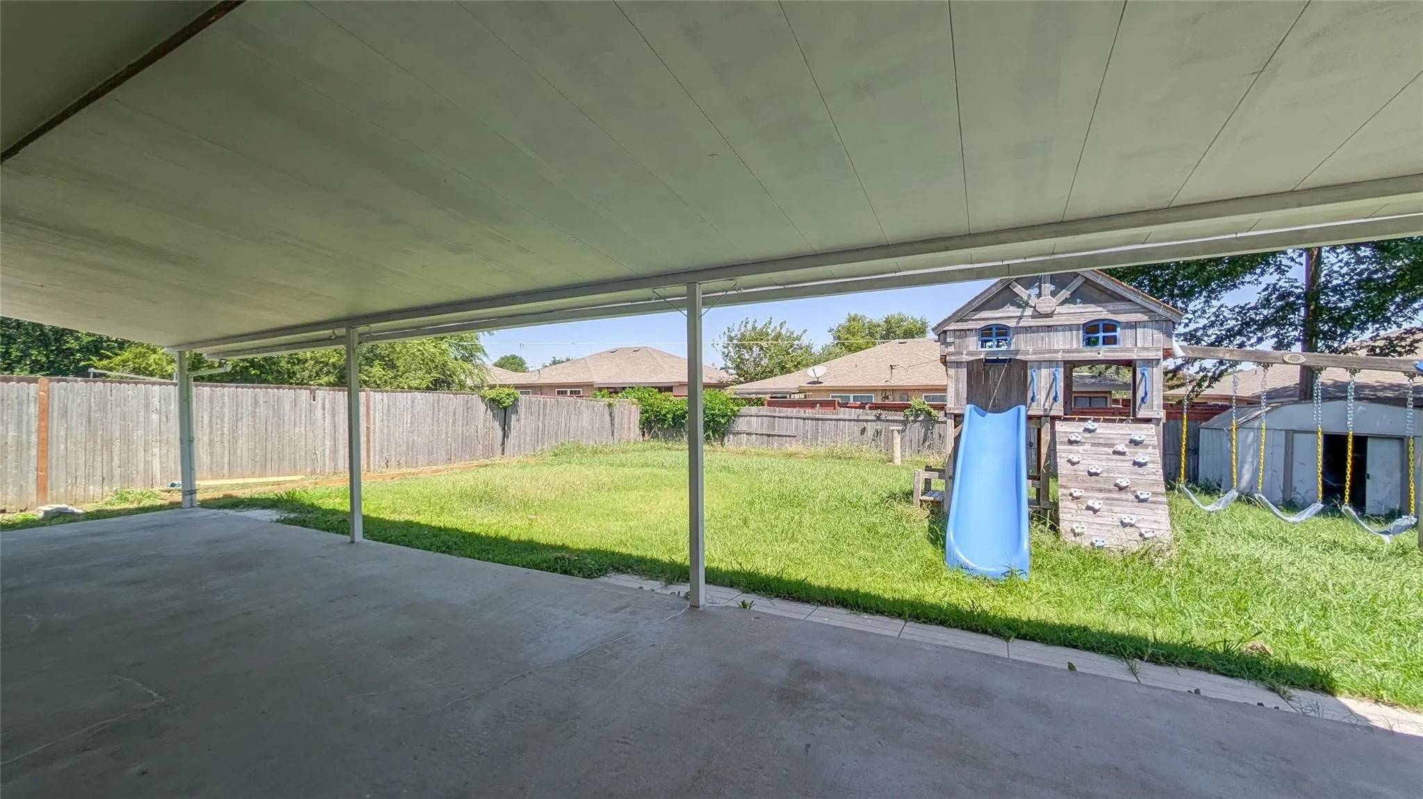 Fenced backyard featuring a playground and a patio