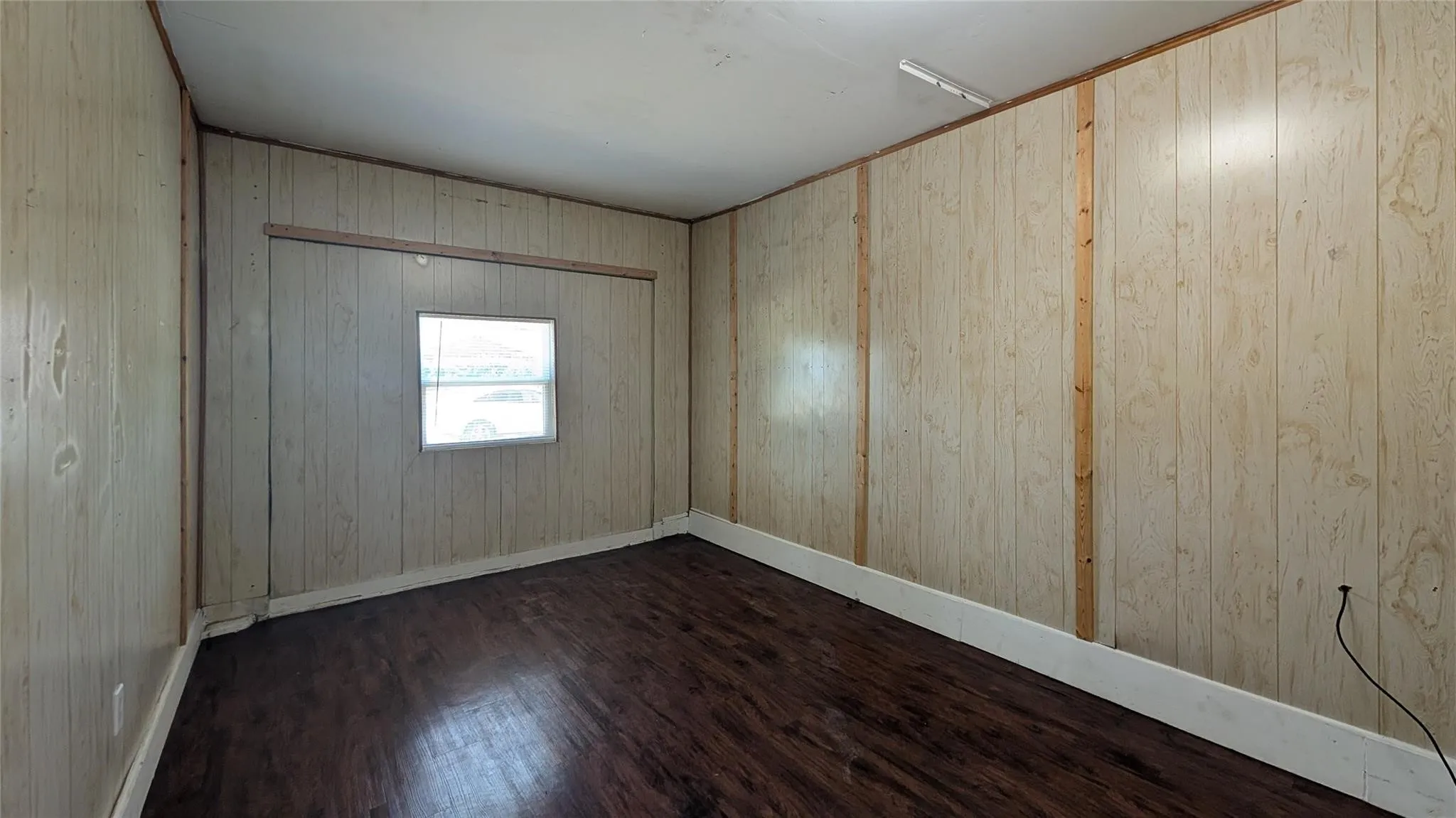Empty room with dark wood-type flooring and wood walls
