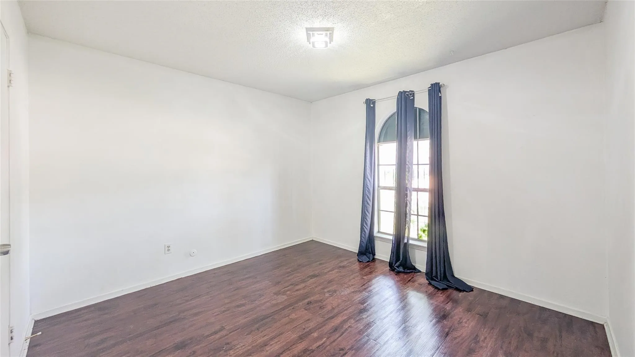 Unfurnished room featuring dark wood-type flooring and a textured ceiling