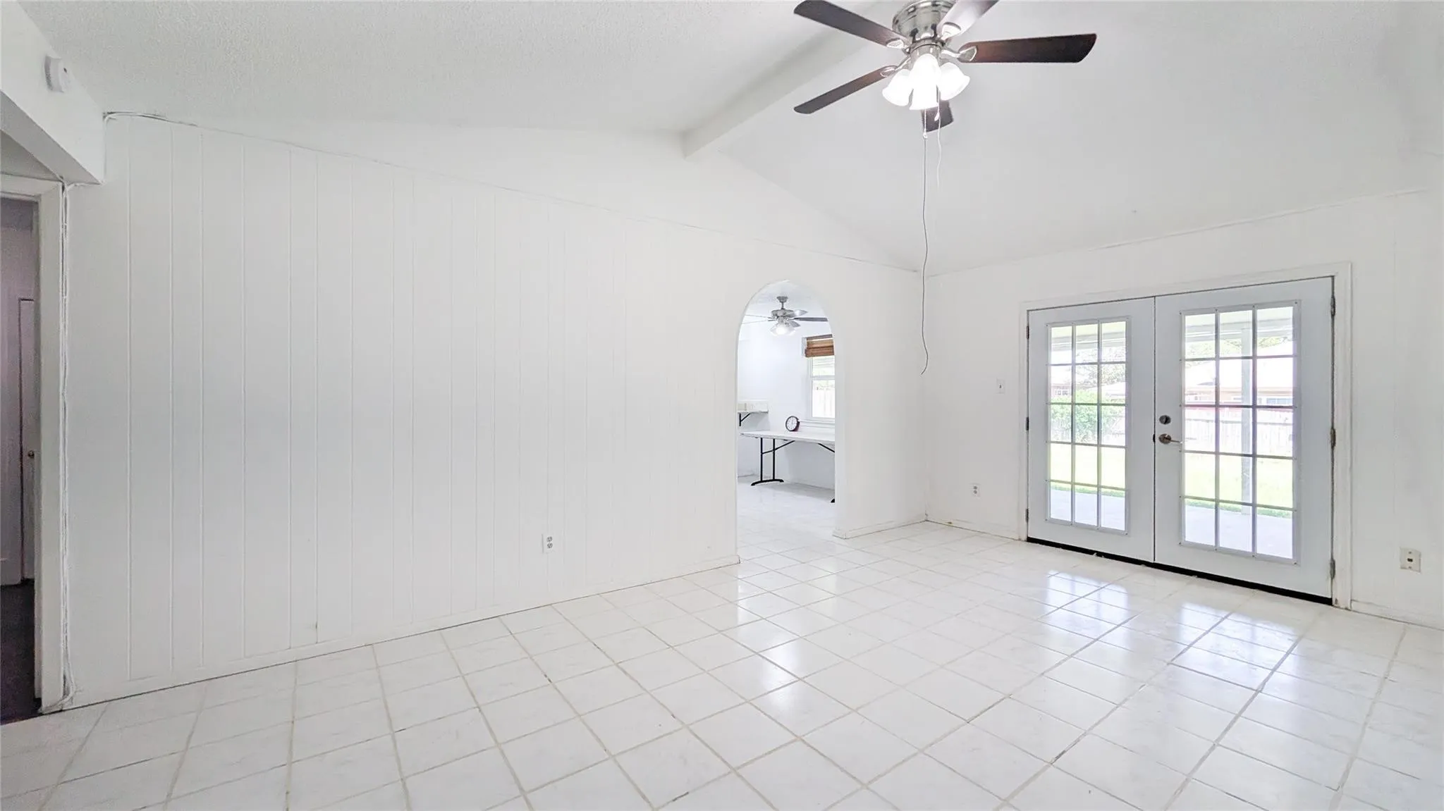 Unfurnished room with a ceiling fan, french doors, beam ceiling, and light tile patterned floors