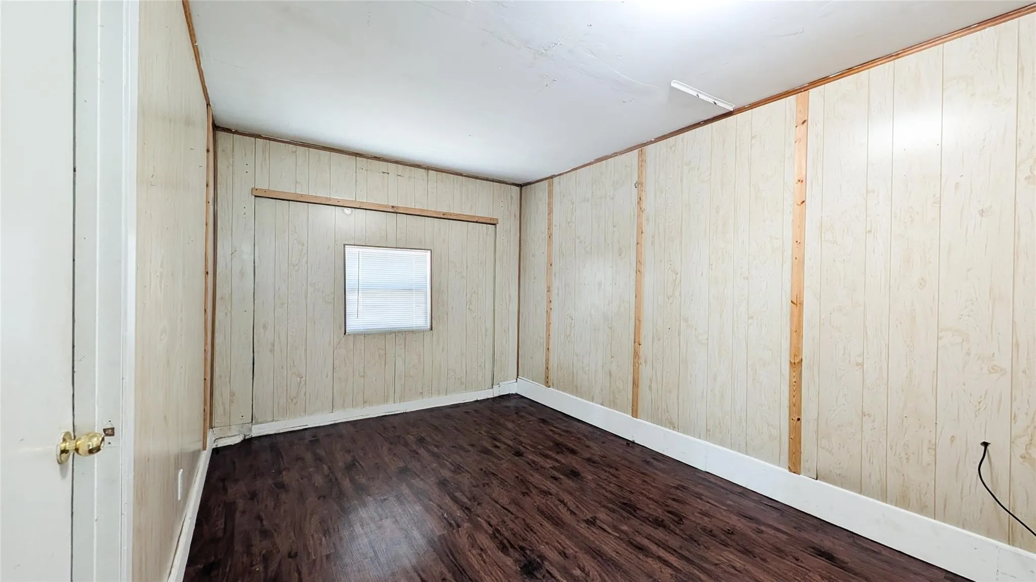 Unfurnished room featuring wooden walls and dark wood-type flooring