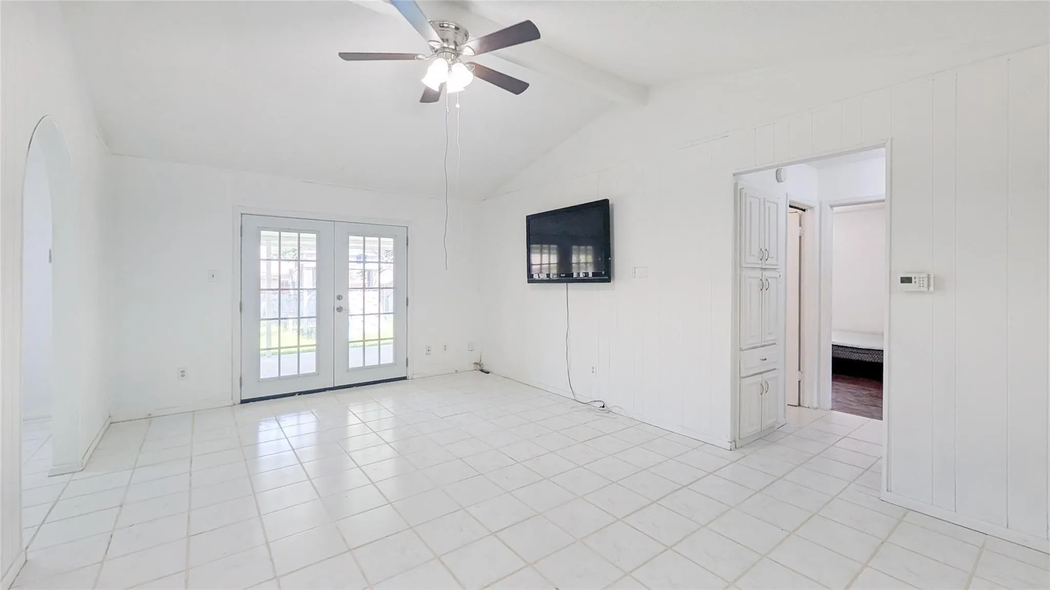 Spare room featuring french doors, ceiling fan, beam ceiling, and light tile patterned floors