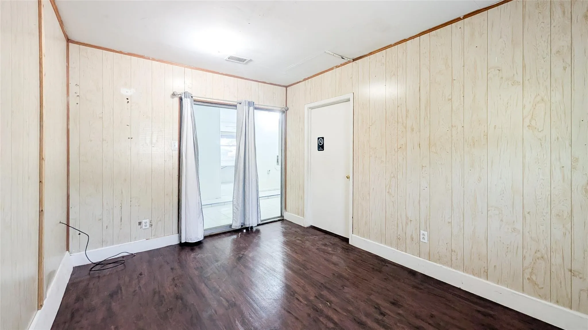 Spare room featuring dark wood-type flooring, wood walls, and ornamental molding