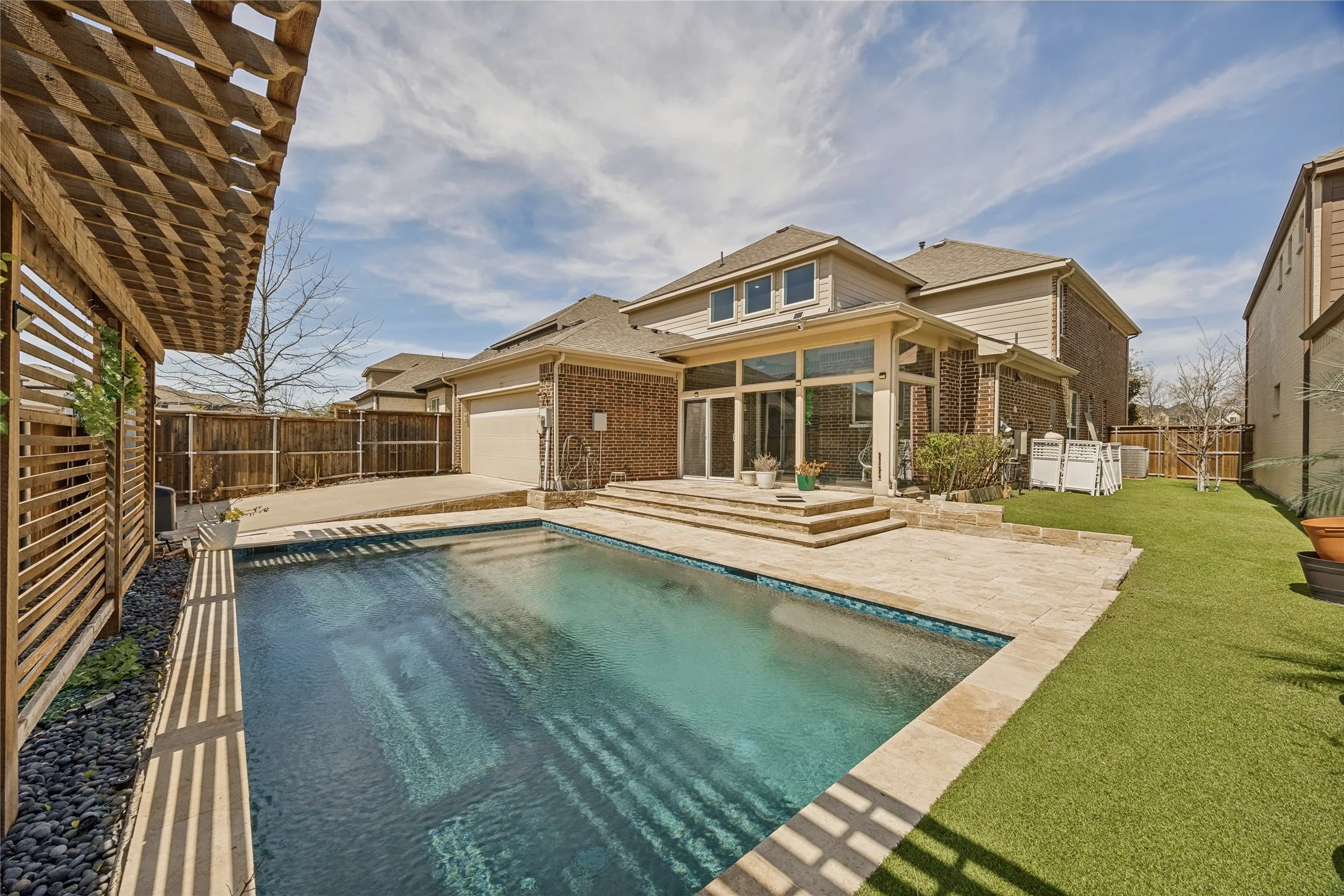 Backyard featuring a rectangular swimming pool with stone coping and a surrounding stone patio