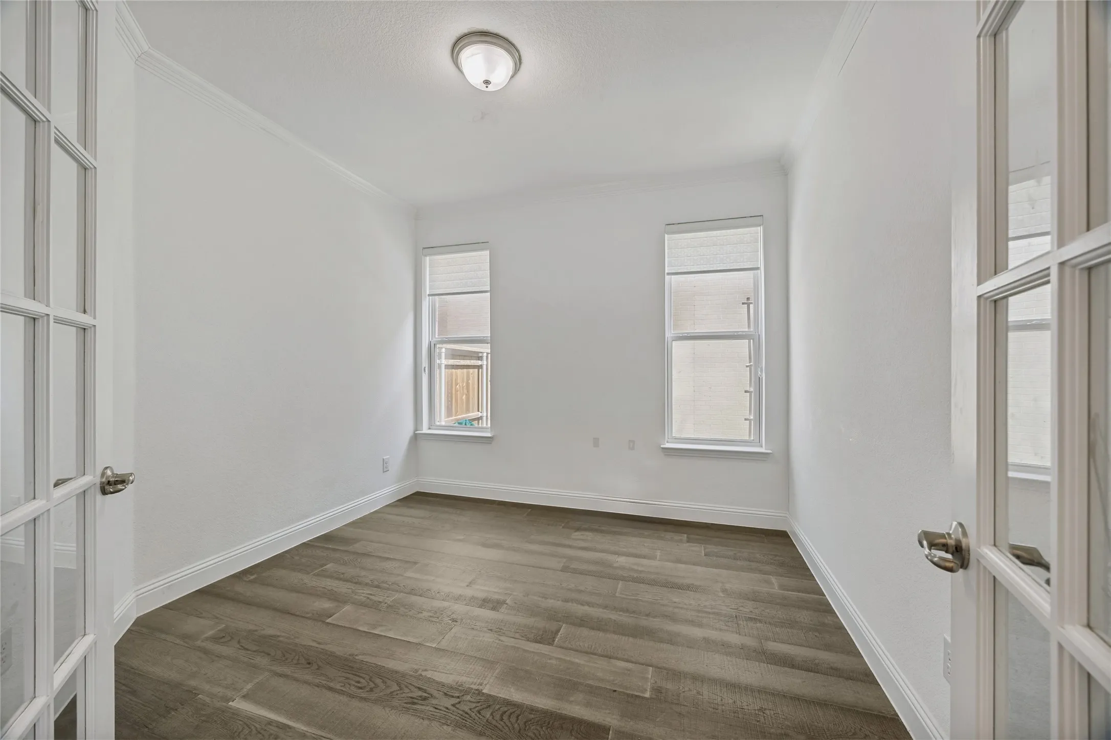 Versatile room featuring wood-finish flooring, crisp white walls, and crown molding