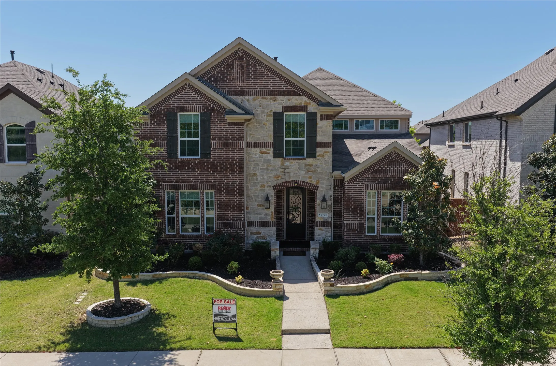 Traditional-style home featuring a brick and stone facade, dark window shutters, and a covered entryway