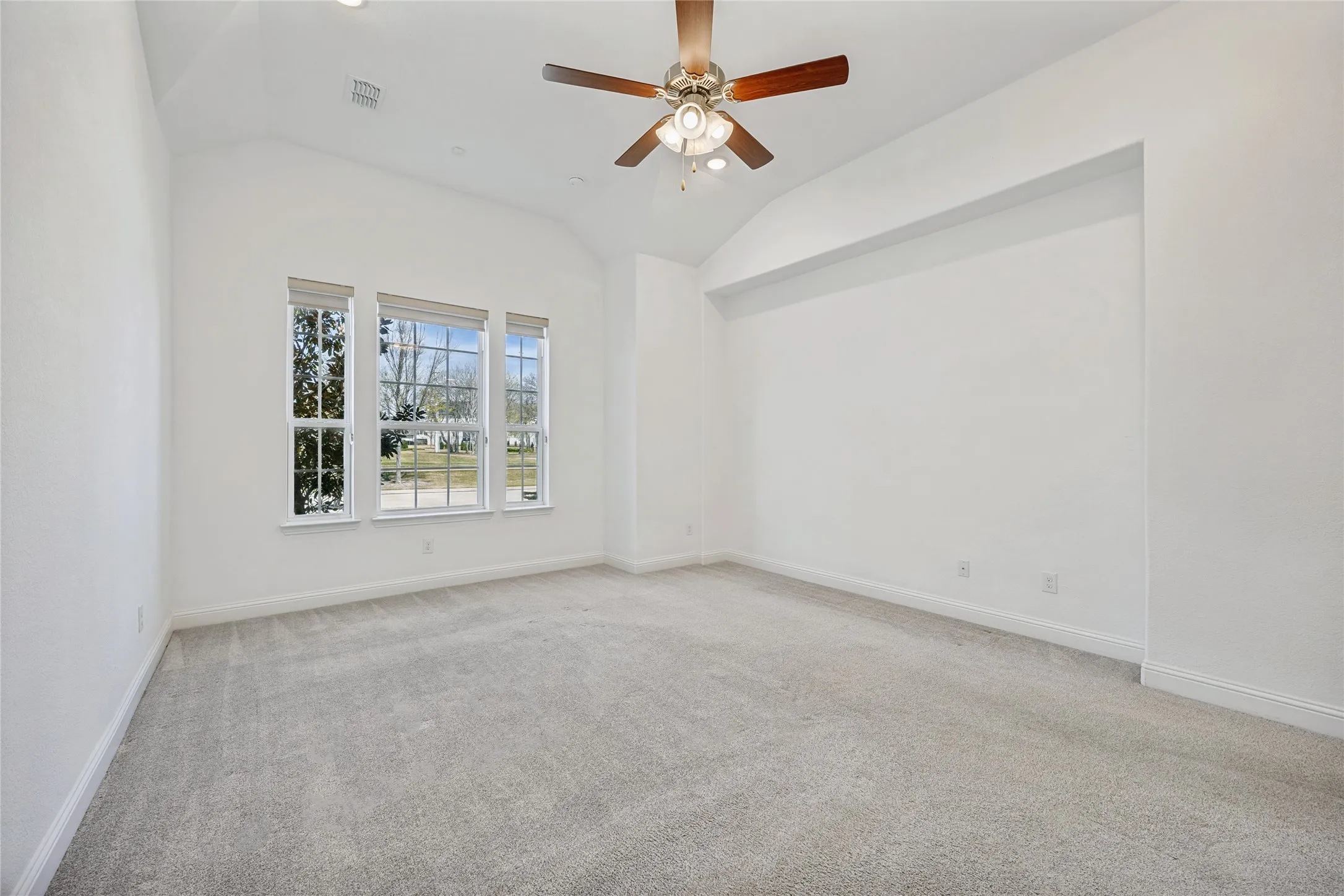 Spacious room featuring vaulted ceilings, a ceiling fan with light fixture, recessed lighting, and a triple window assembly