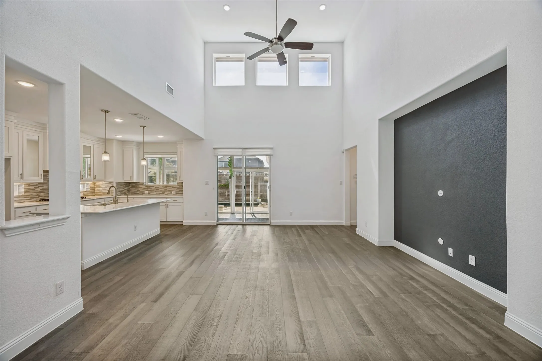 Spacious living area featuring high ceilings, wood-finish flooring, and recessed lighting