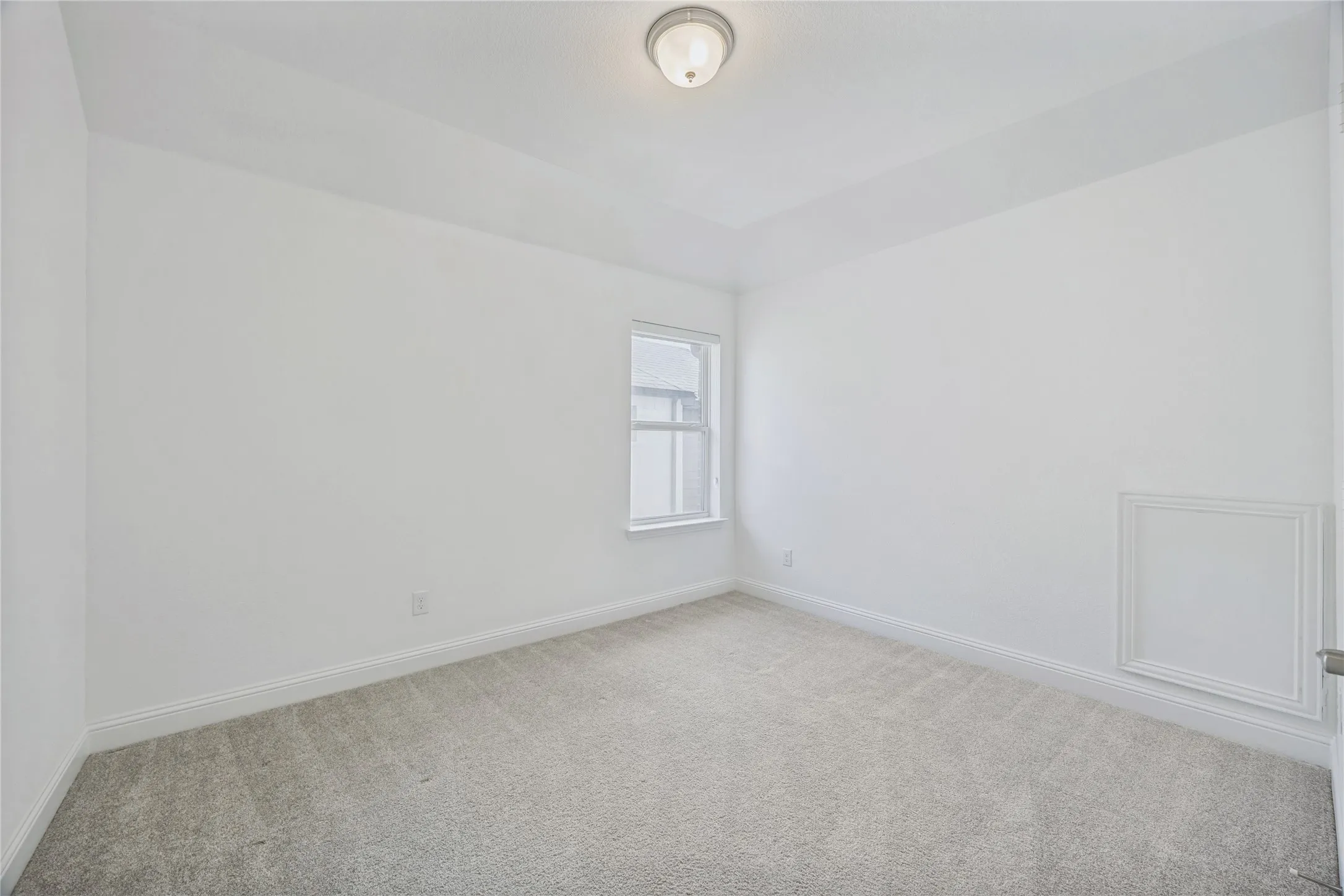 Neutral tone carpeted room featuring a single window with vertical blinds, a tray ceiling, and a flush mount light fixture