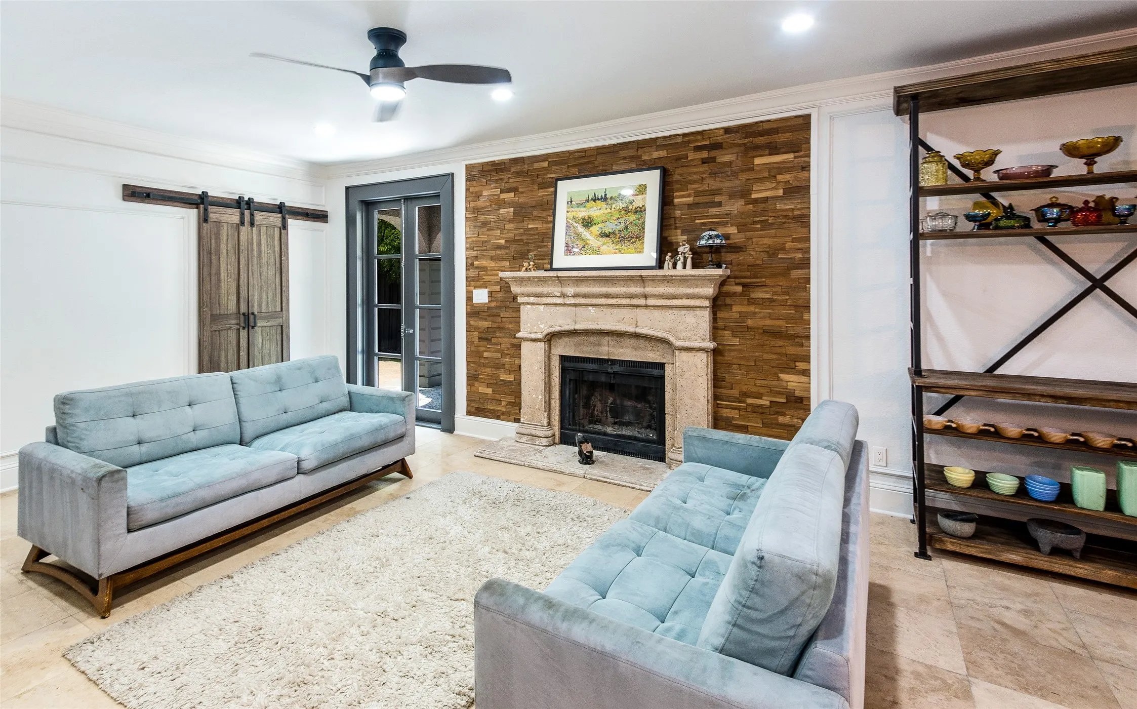 Living room with a barn door, a ceiling fan, a fireplace, and ornamental molding