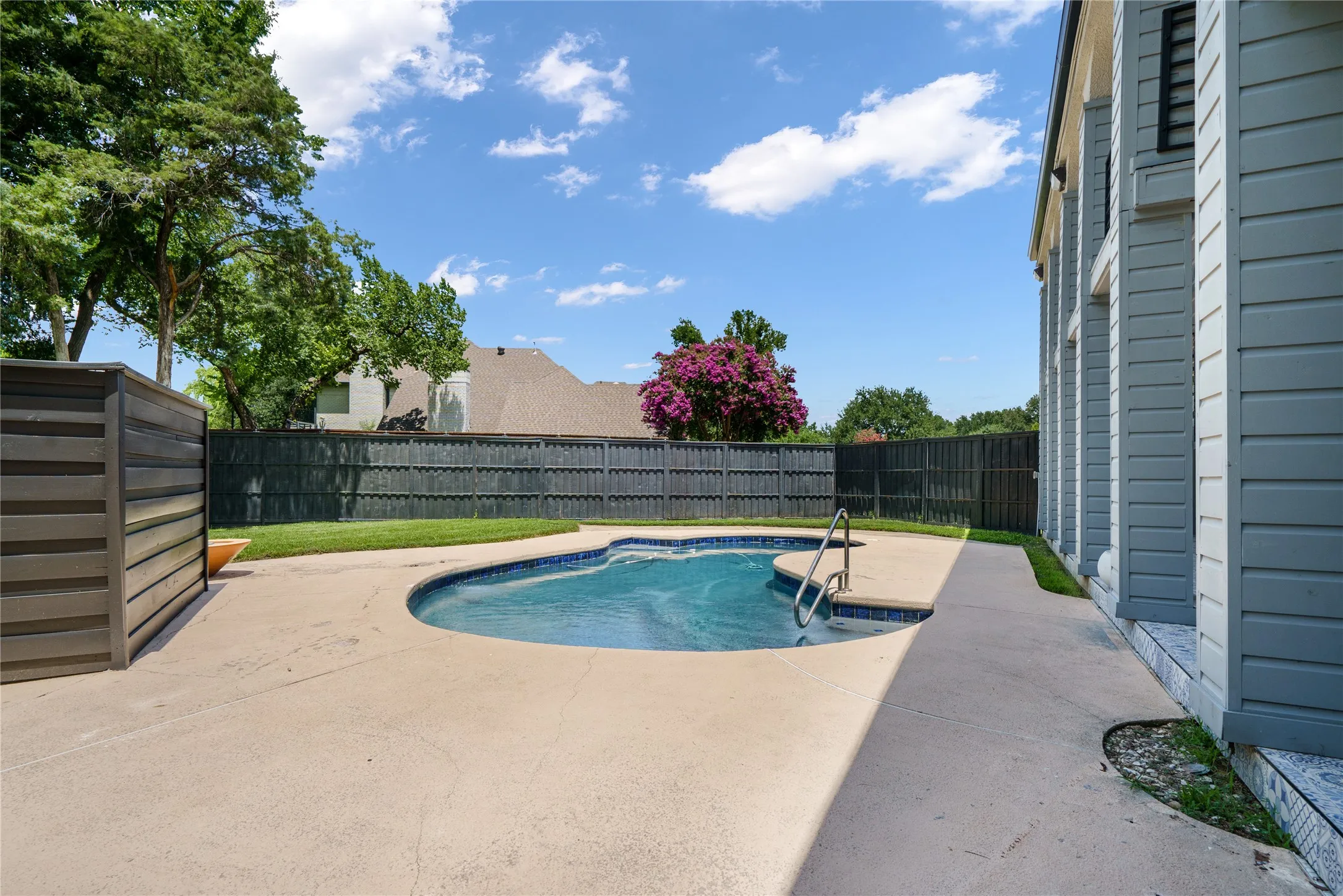 View of swimming pool with patio surround and a fenced backyard