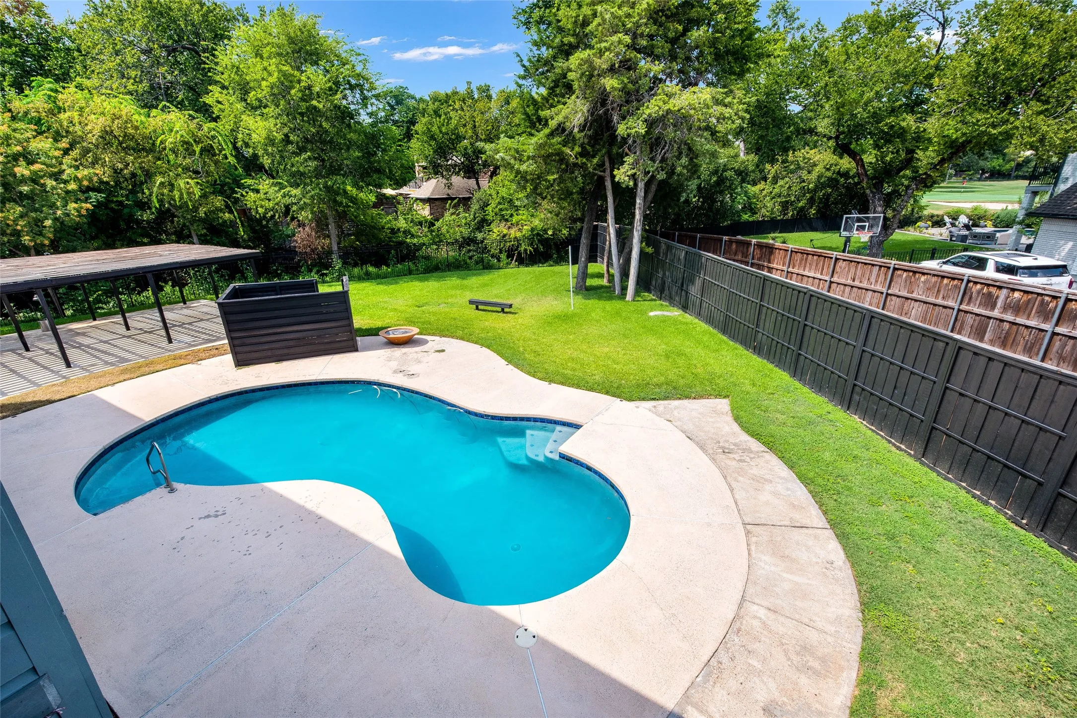 View of swimming pool featuring patio surround, a fenced backyard, and view of wooded area