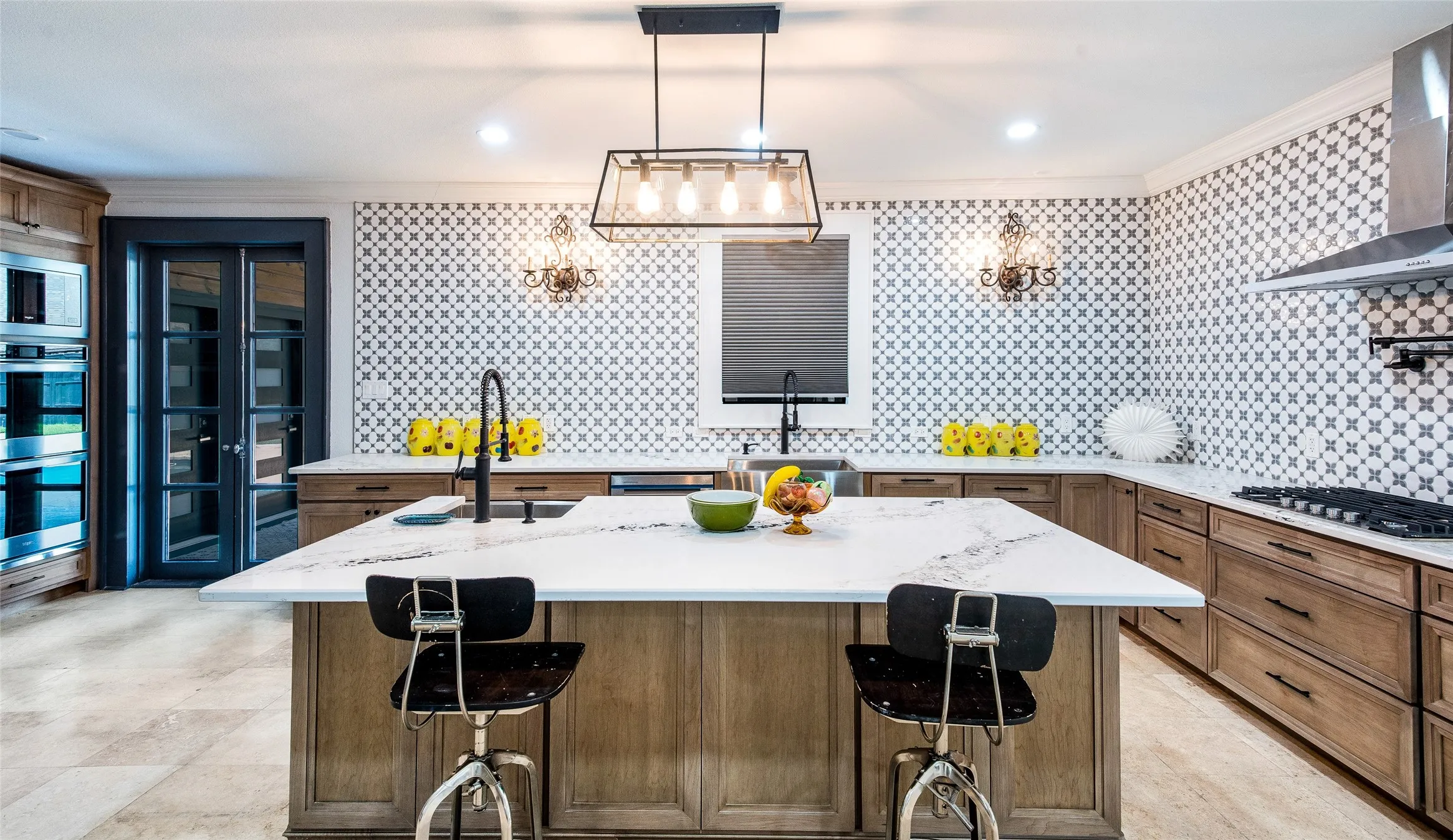 Kitchen with an island with sink, wood finish cabinets, decorative backsplash, stainless steel appliances, and hanging light fixtures
