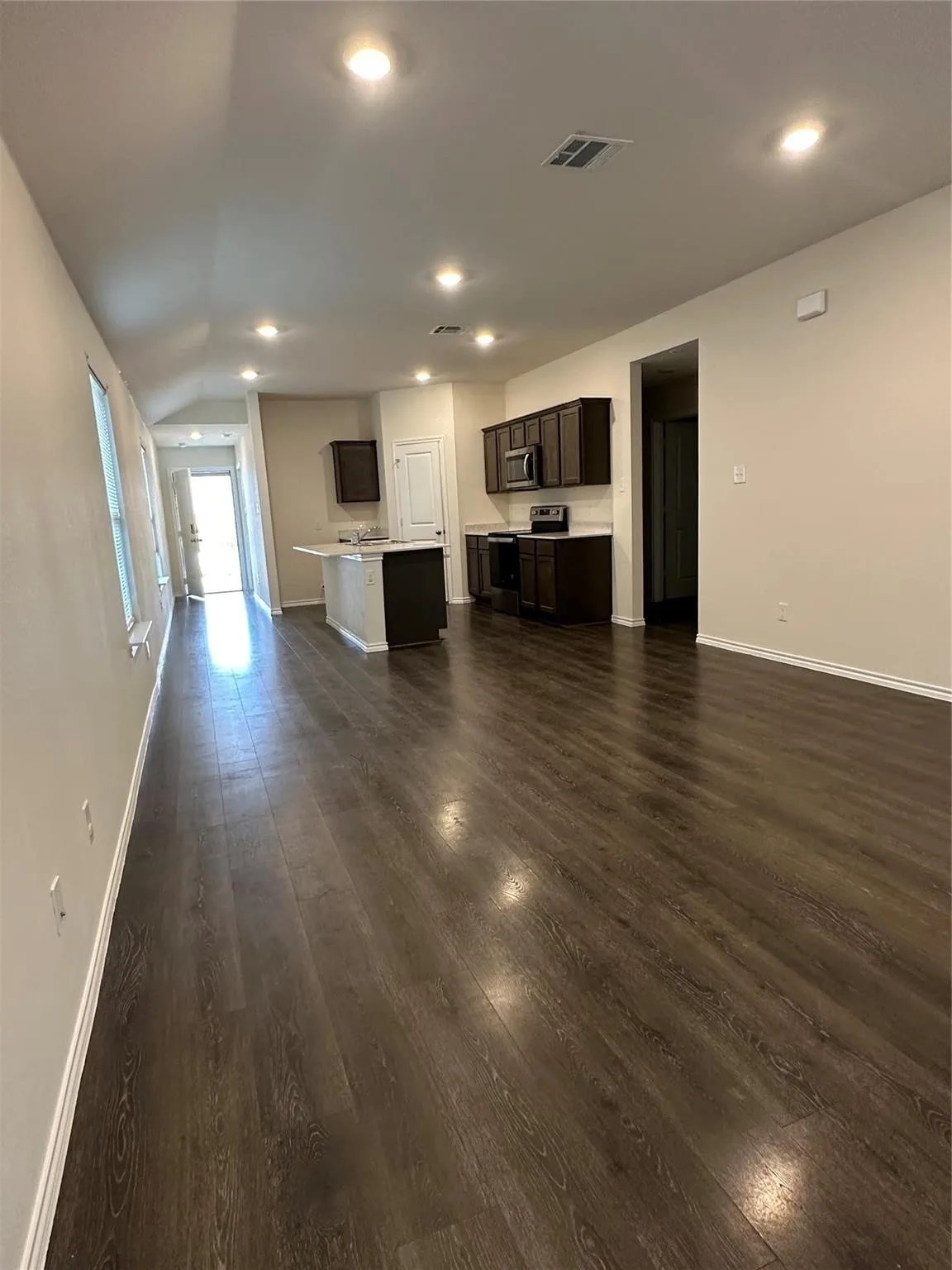 Unfurnished living room with dark wood-style floors, lofted ceiling, and recessed lighting