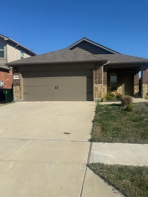 Ranch-style home featuring concrete driveway, an attached garage, brick siding, and stone siding