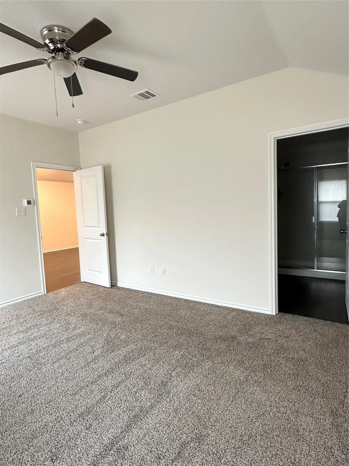 Unfurnished bedroom featuring ceiling fan, dark carpet, and lofted ceiling