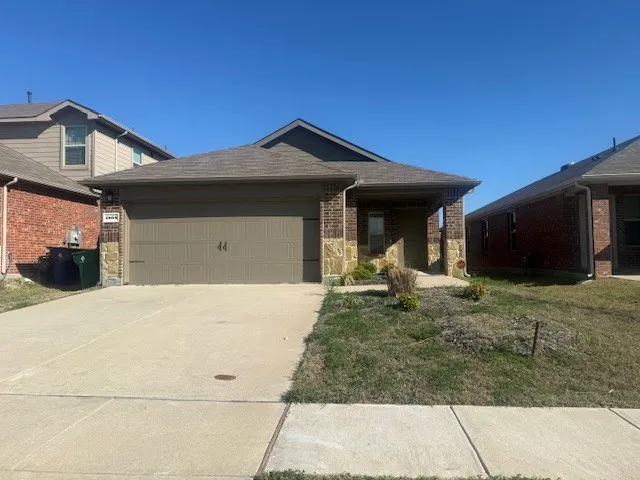 Ranch-style house featuring an attached garage, concrete driveway, brick siding, and stone siding