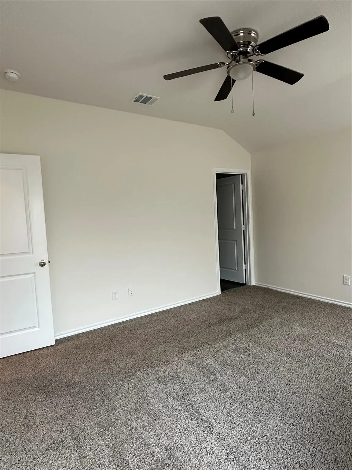 Spare room with lofted ceiling, dark carpet, and a ceiling fan