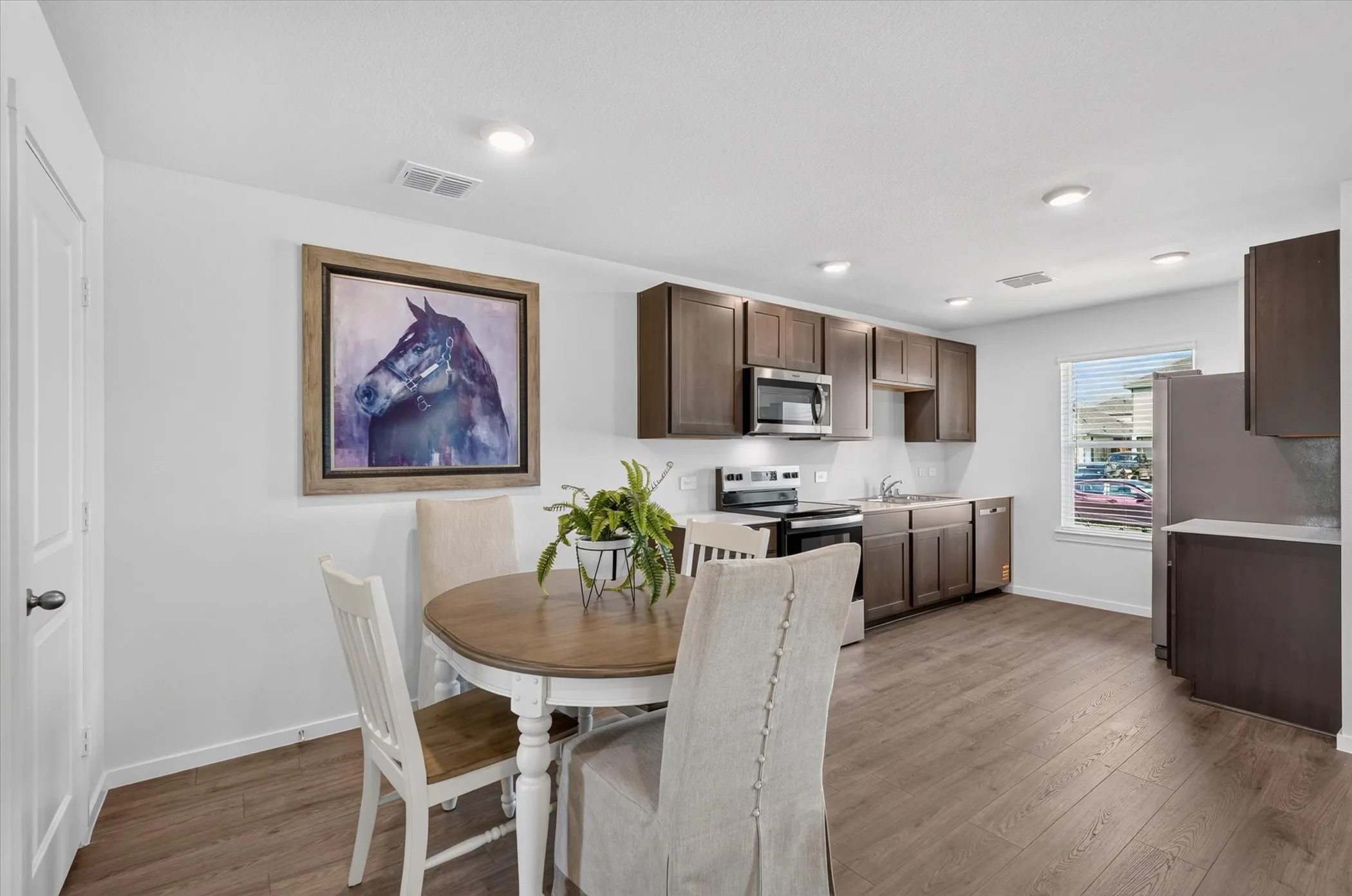 Recessed lighting illuminates the kitchen and dining area with wood-finish flooring