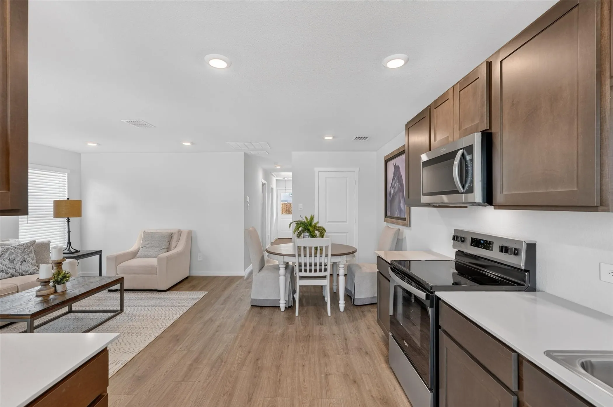 Contemporary kitchen featuring wood-finish cabinetry, stainless steel appliances, and light-toned countertops