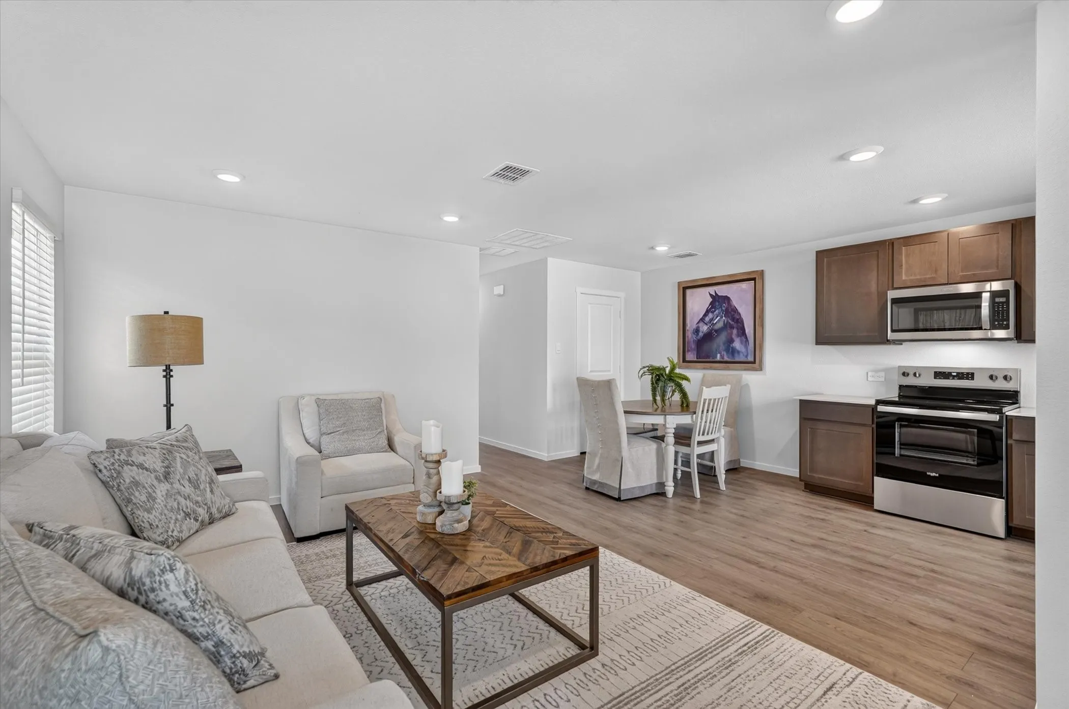 Open-concept living space featuring wood-finish flooring, recessed lighting, and white walls