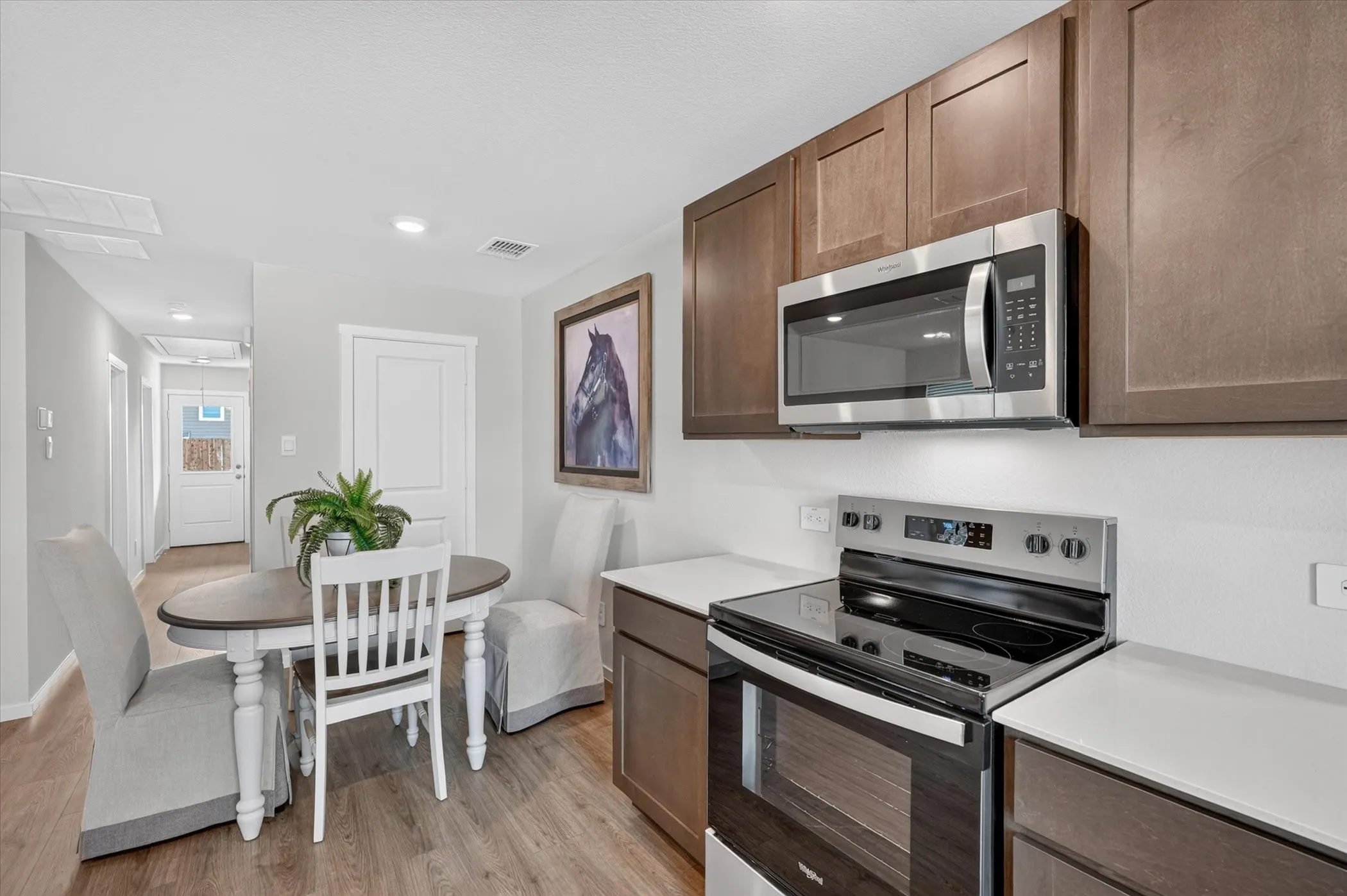 Kitchen with stainless steel appliances, dark wood-finish cabinetry, light countertops, and wood-finish flooring