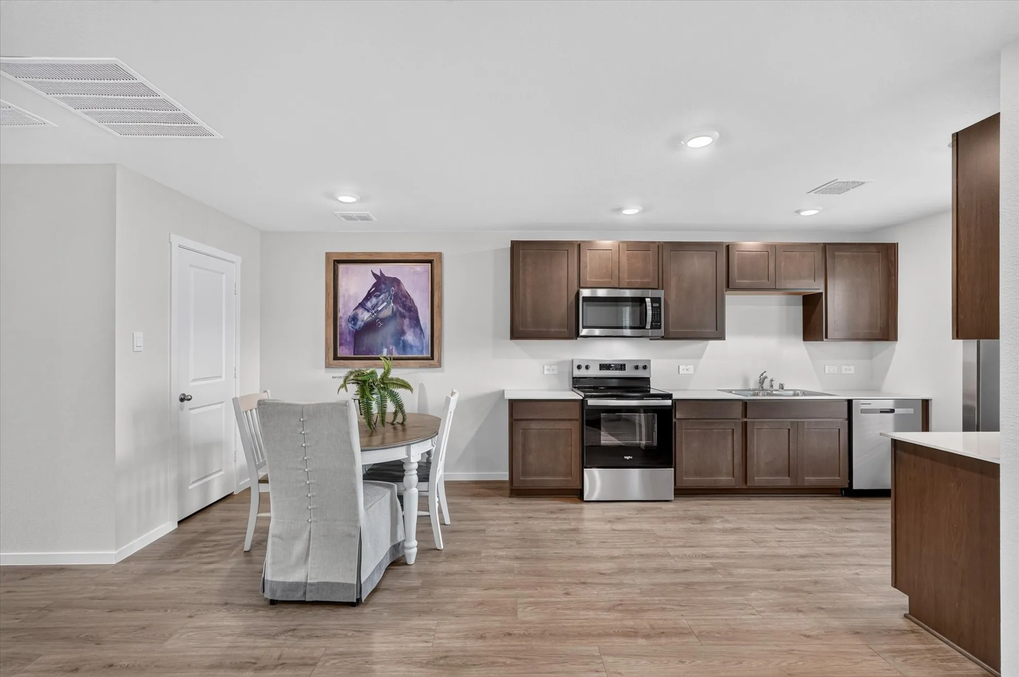 Wood-finish flooring throughout, recessed lighting, wood cabinetry, stainless steel appliances, and solid surface countertops