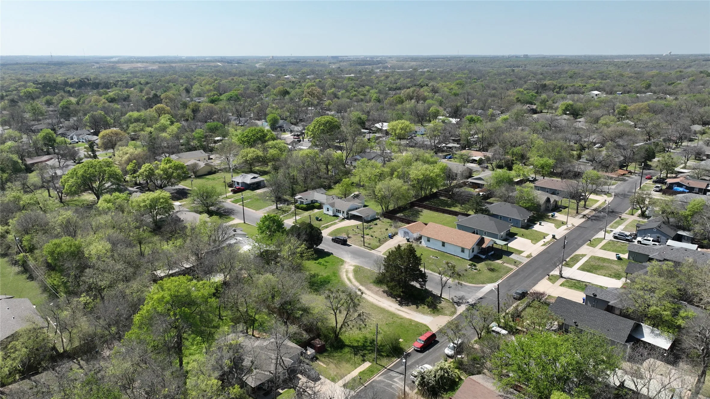Aerial perspective of suburban area featuring a heavily wooded area