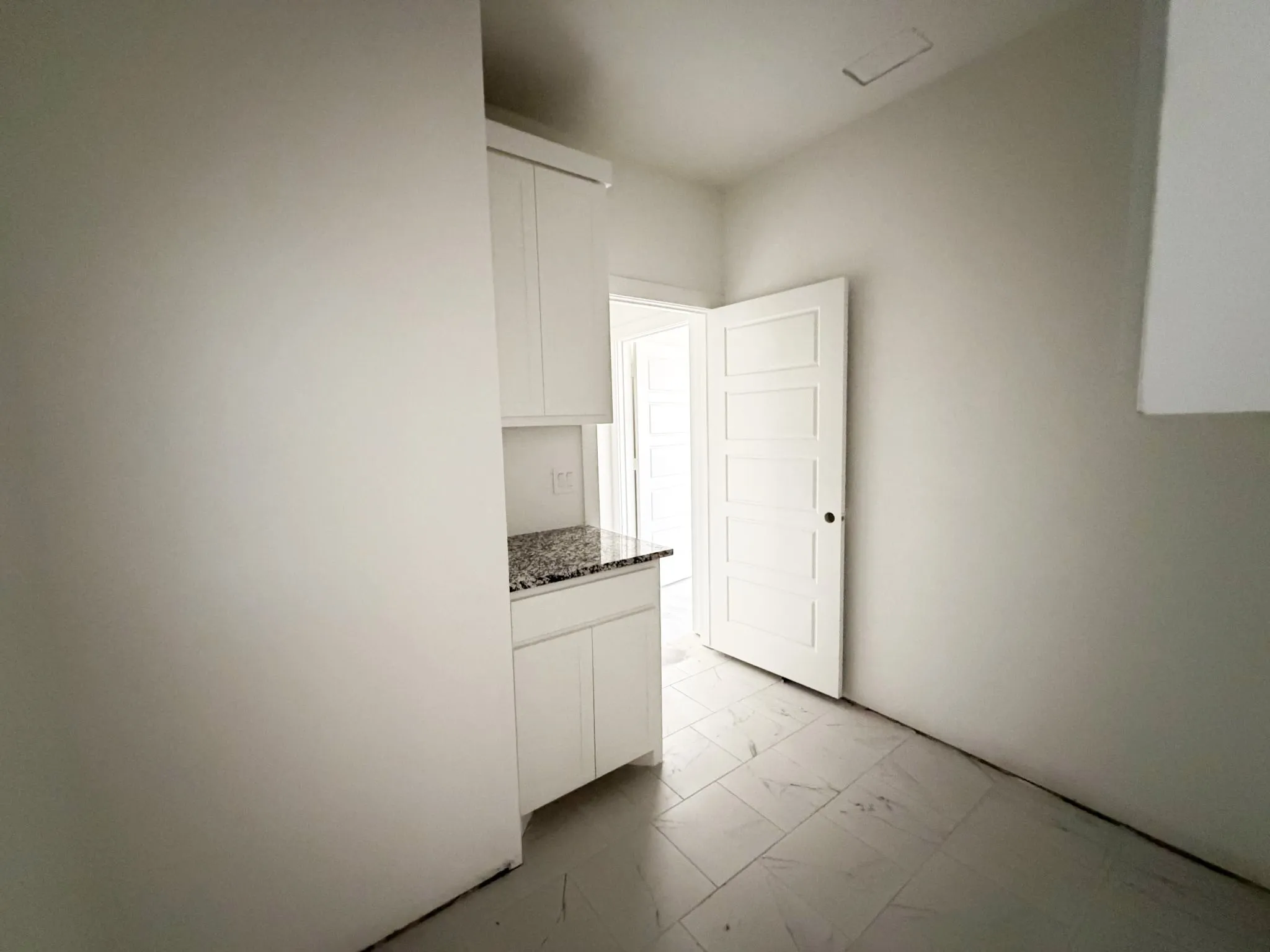 White cabinetry with a polished stone countertop and tiled flooring